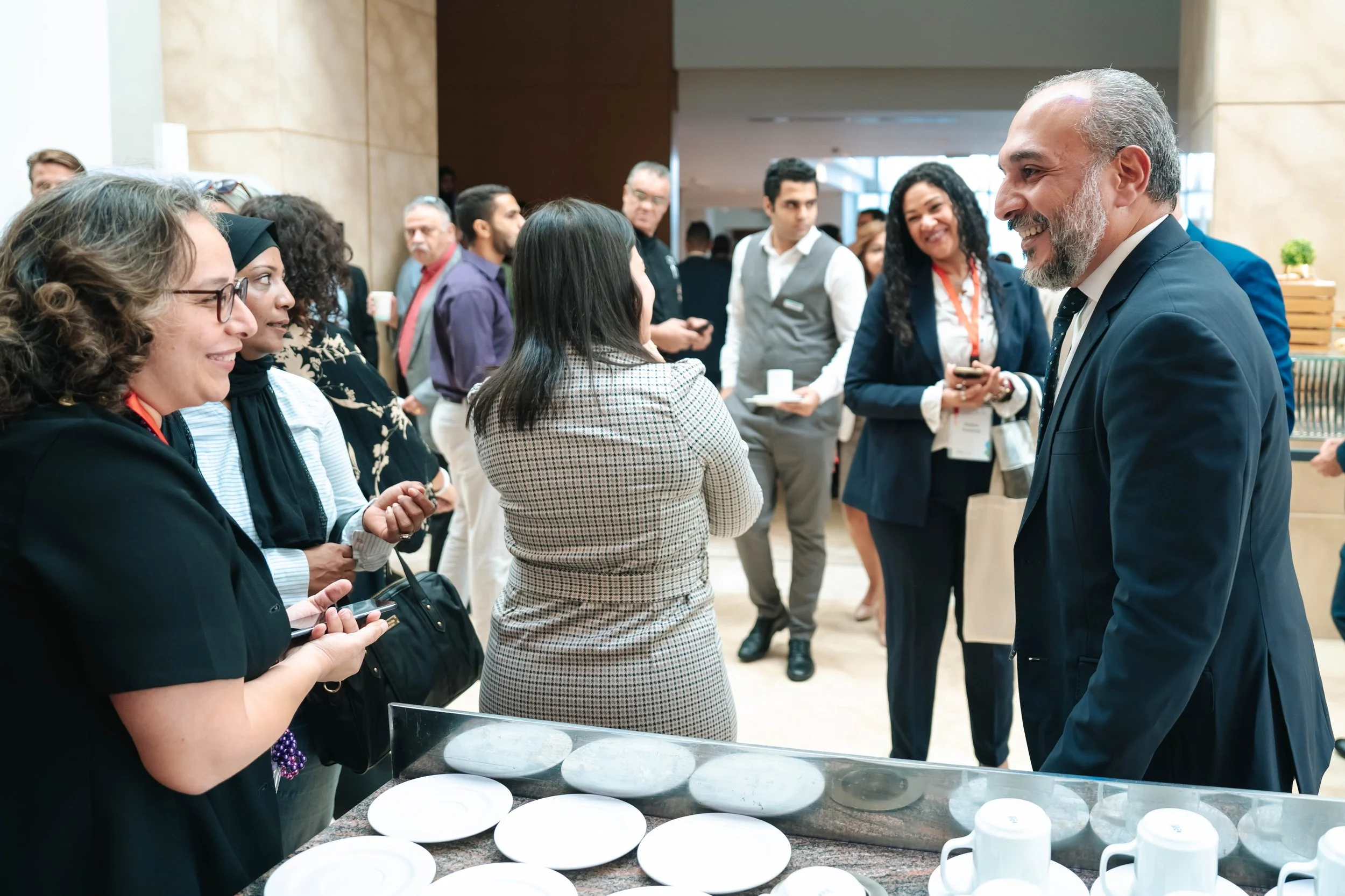 People engaging in conversation at a professional networking event, with a table of cups and plates in the foreground at the Regional Sustainable Development Forum, First Edition