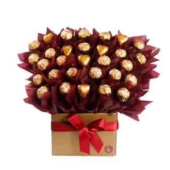 A gift box filled with Ferrero Rocher chocolates, wrapped in gold foil and arranged with red decorative paper, topped with a red ribbon bow.