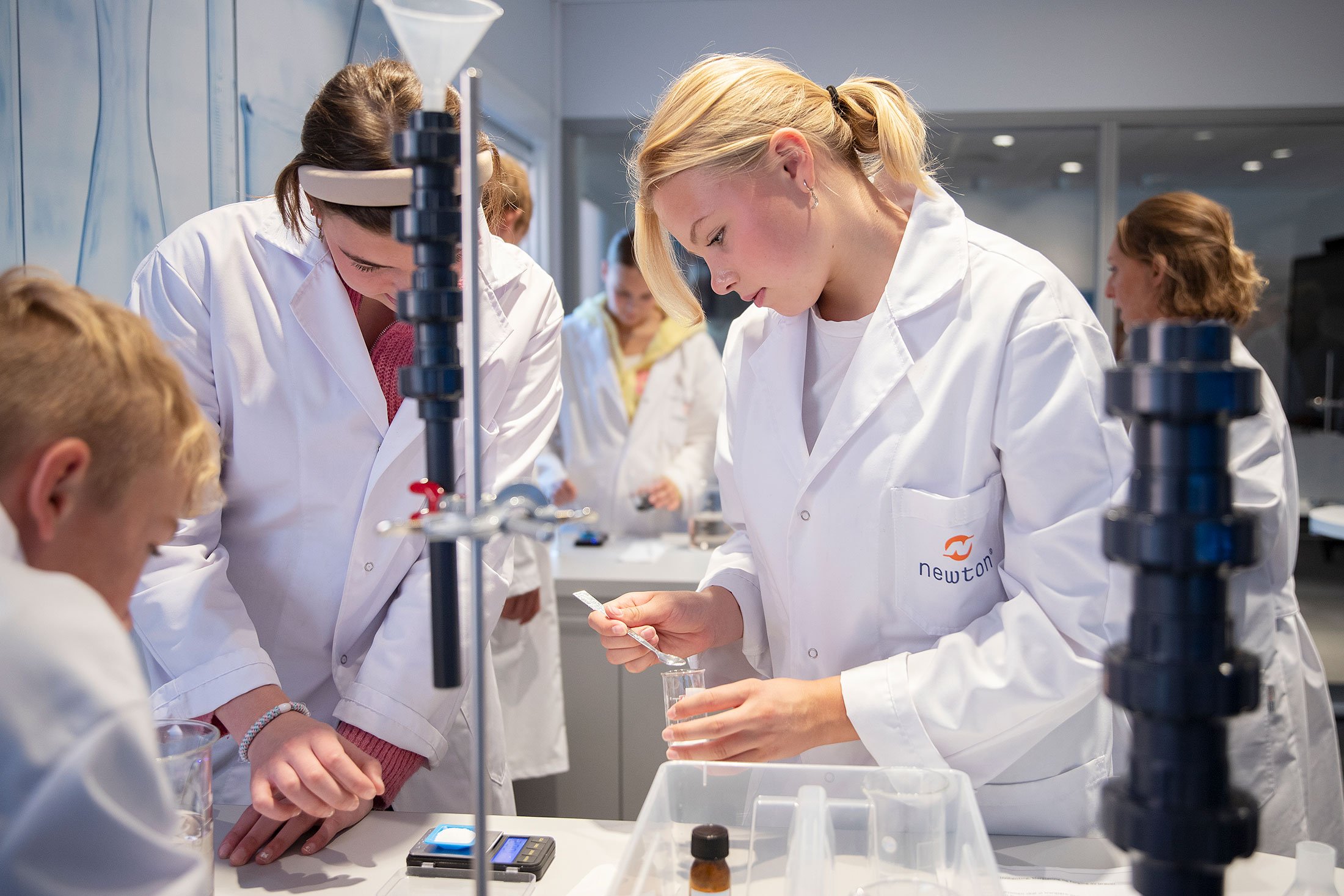 Newton-elever jobber med laboratorieutstyr.