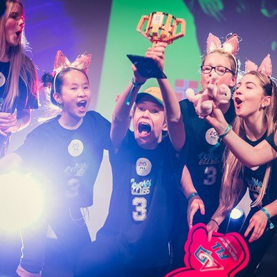 En gruppe unge barn løfter FIRST LEGO league trofeet.