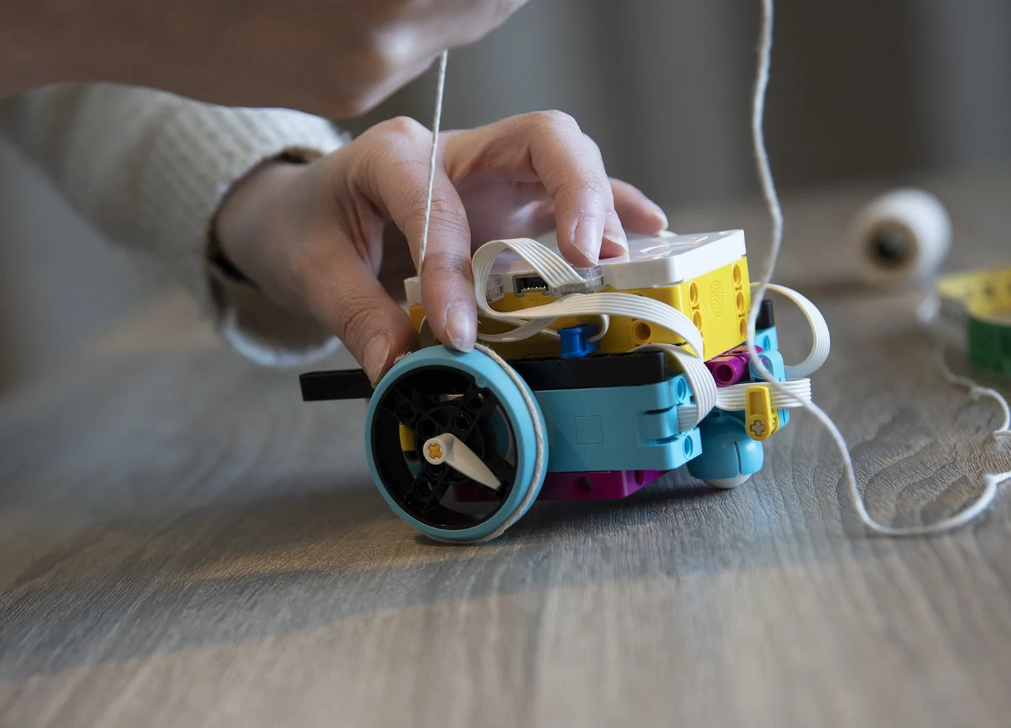 Person som bygger en robot med fargede LEGO- deler og ledninger.