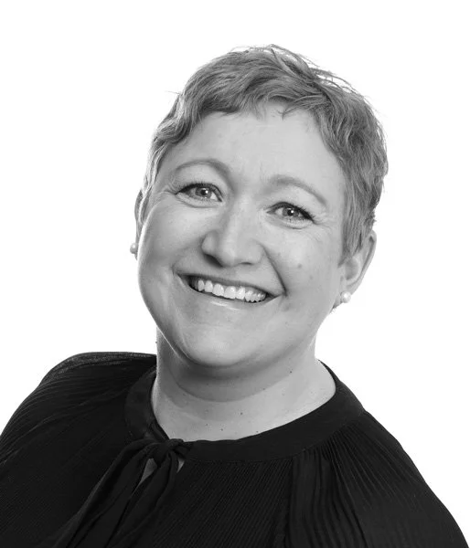 Portrett av en smilende kvinne med kort, lyst hår i svart og hvitt.