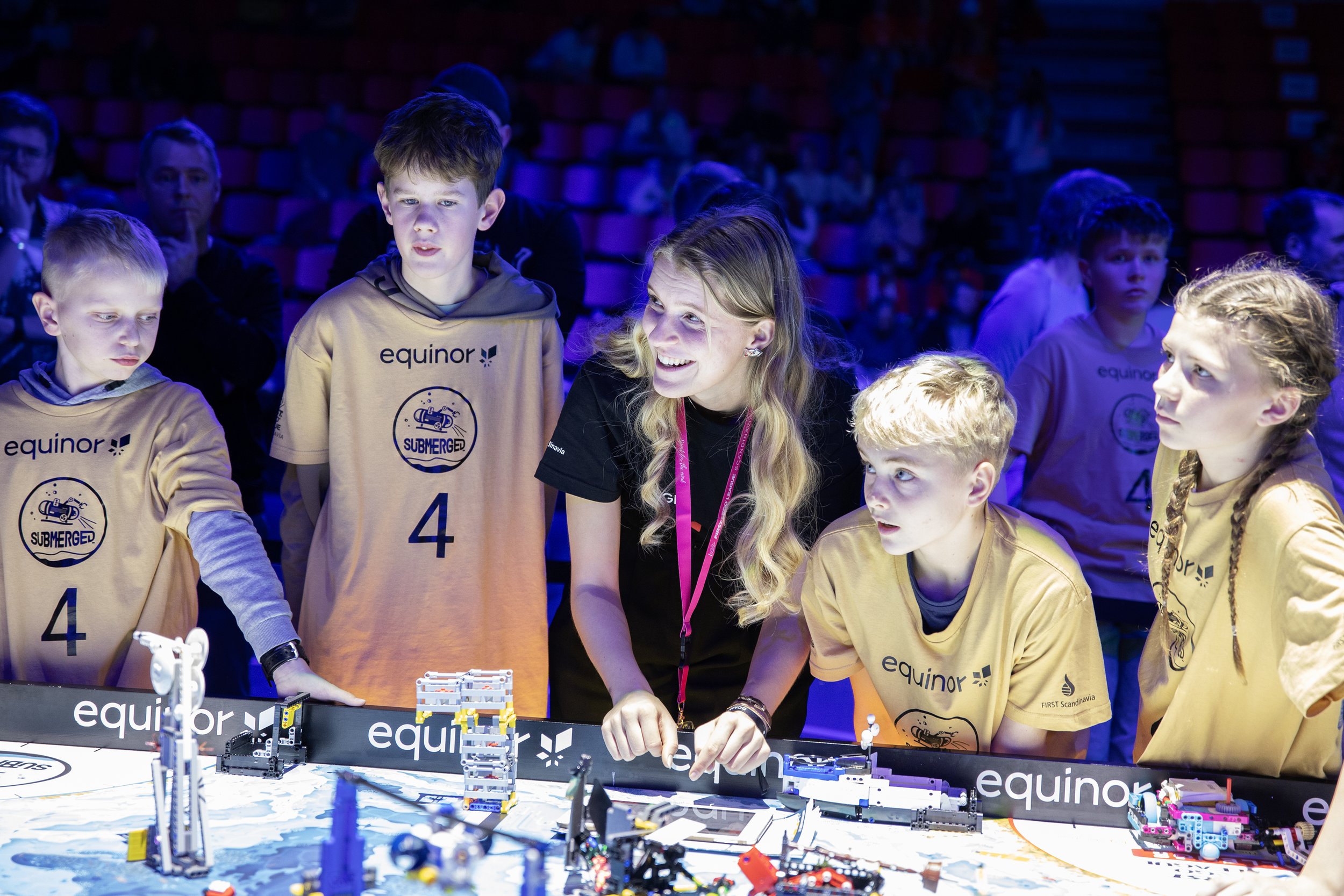 FIRST LEGO League dommer og barn under robot konkurranse.