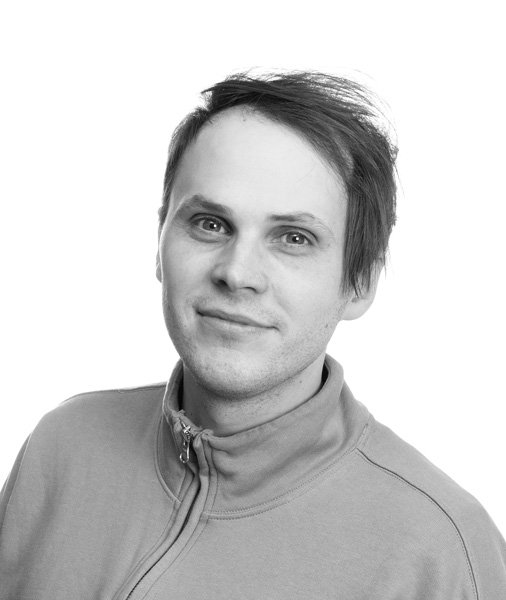 Portrett av en ung mann med svart hår iført en lysulla turtleneck, smilende mot kameraet, mot en hvit bakgrunn.