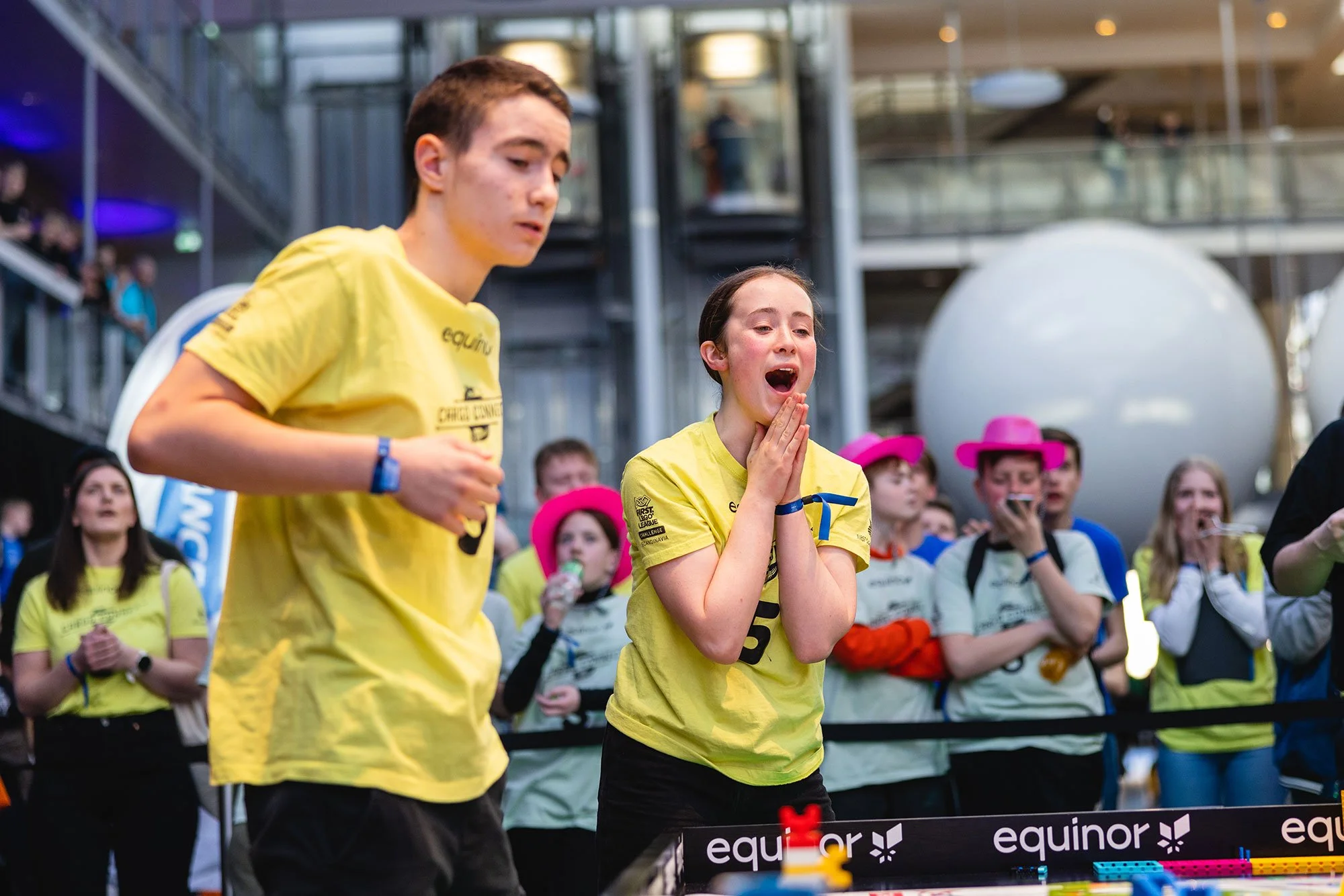 To unge mennesker i gule t-skjorter deltar i FIRST LEGO League.