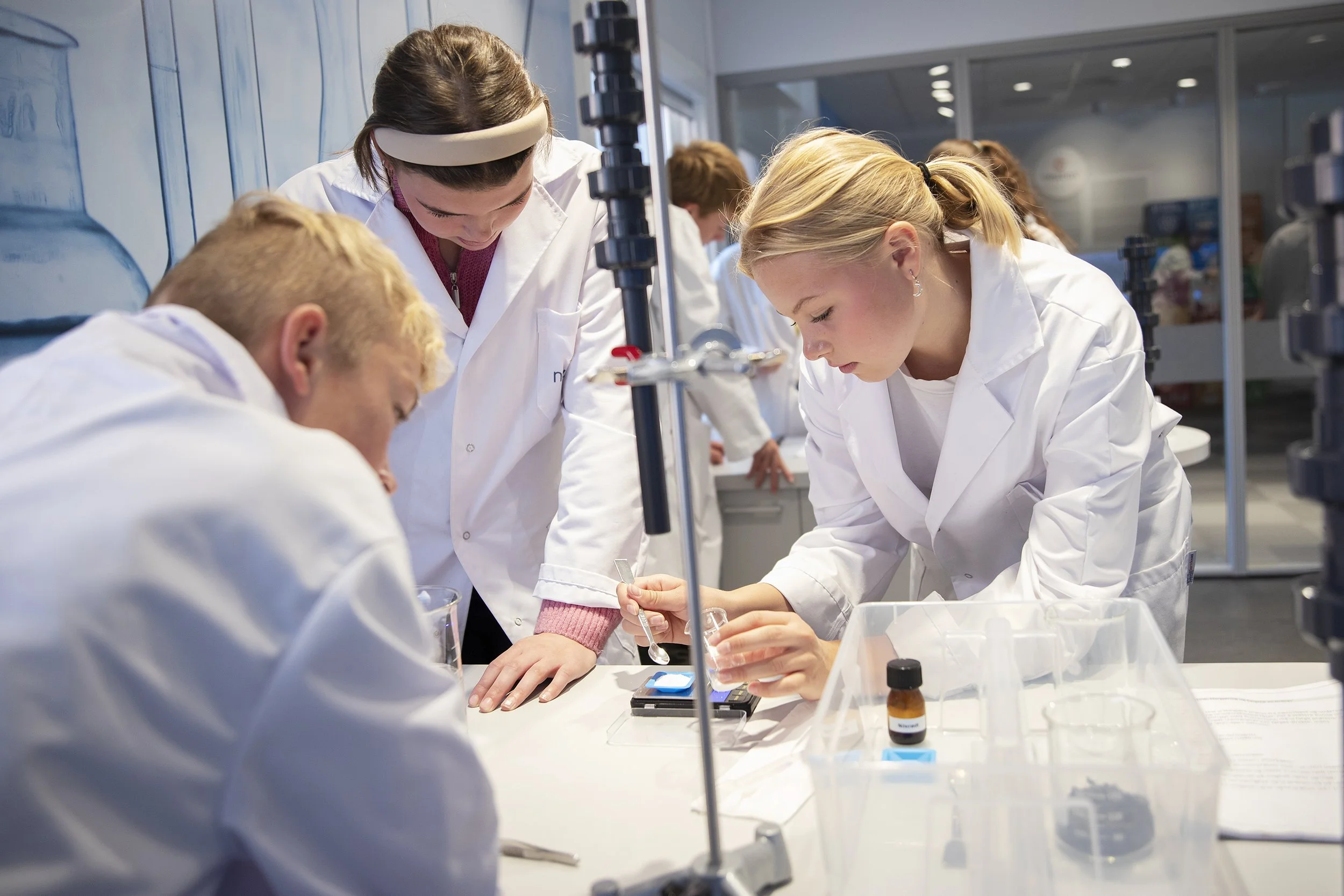 Forskere i laboratoriet utfører eksperimenter med ulike kjemikalier og utstyr.