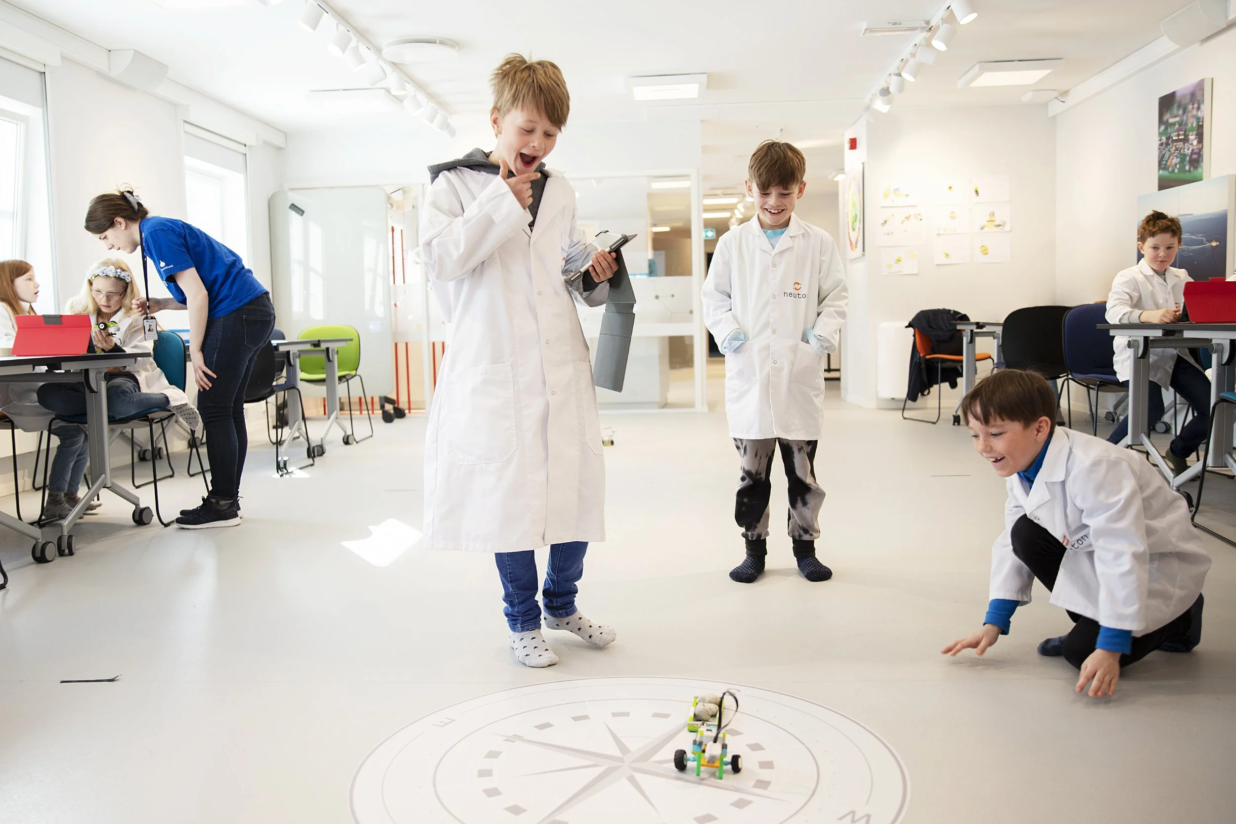 Newton-elever i forsknings frakker som er glade over LEGO robot.