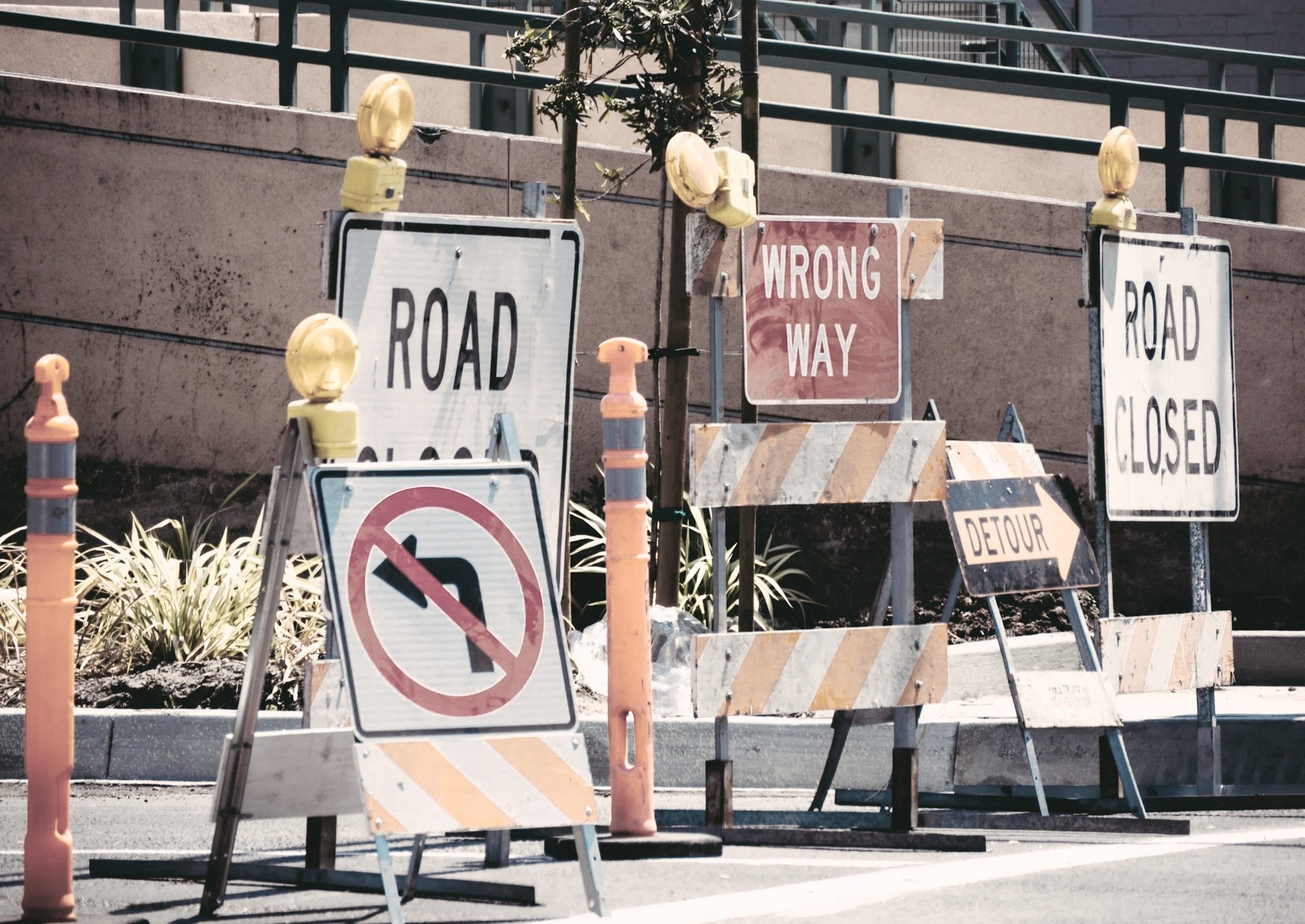 Various construction and road closed signs with orange and yellow safety cones and barriers blocking the street.
