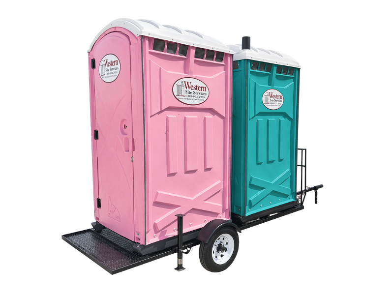 Two portable toilets, one pink and one teal, mounted on a trailer with wheels, labeled Western Site Services.