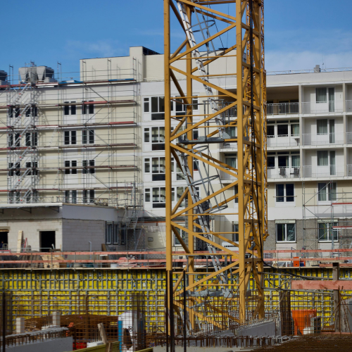 Construction site with a yellow crane and a multi-story building under construction.
