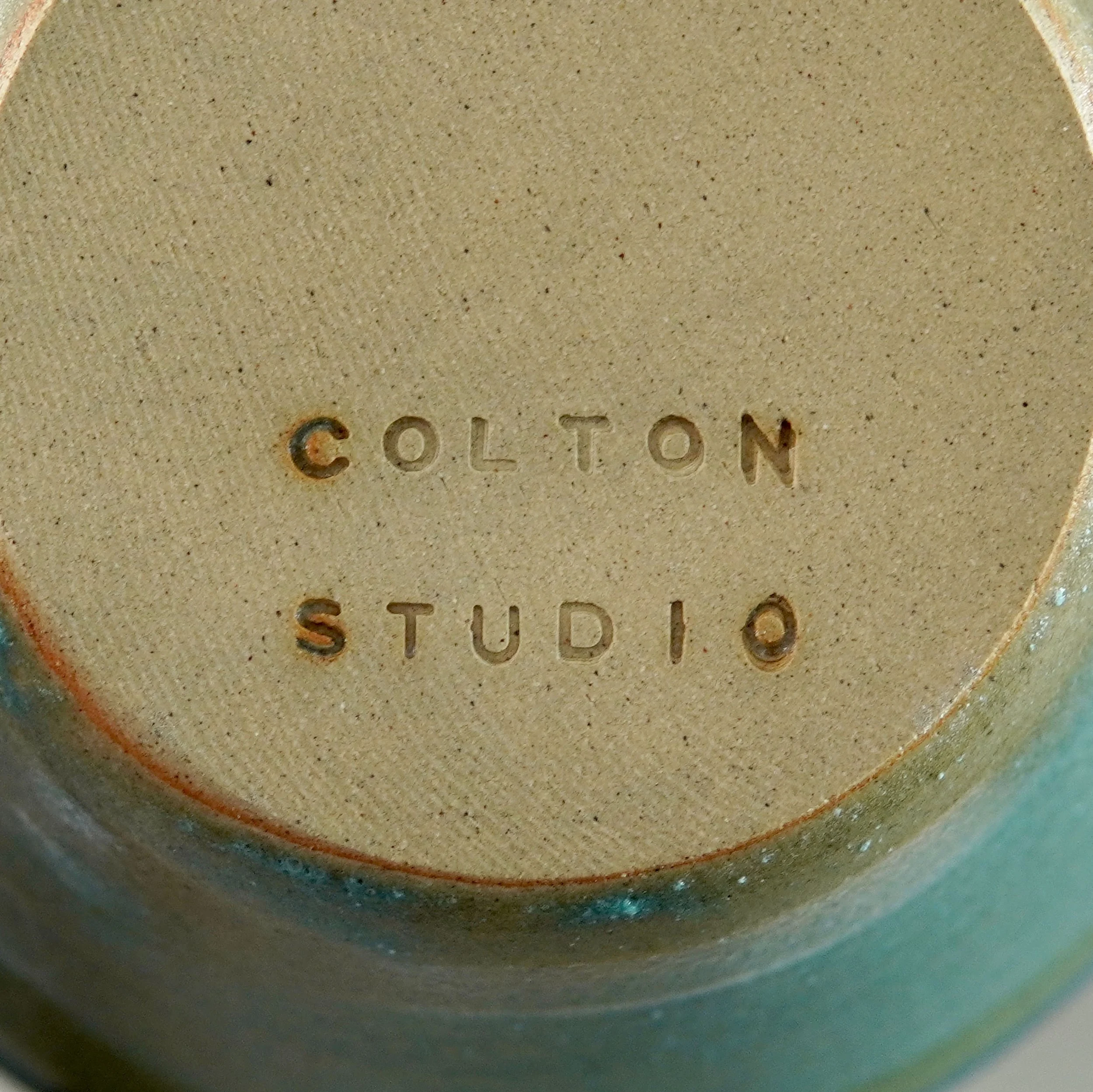 Close-up of the bottom of a ceramic piece engraved with the words 'COLTON STUDIO'.