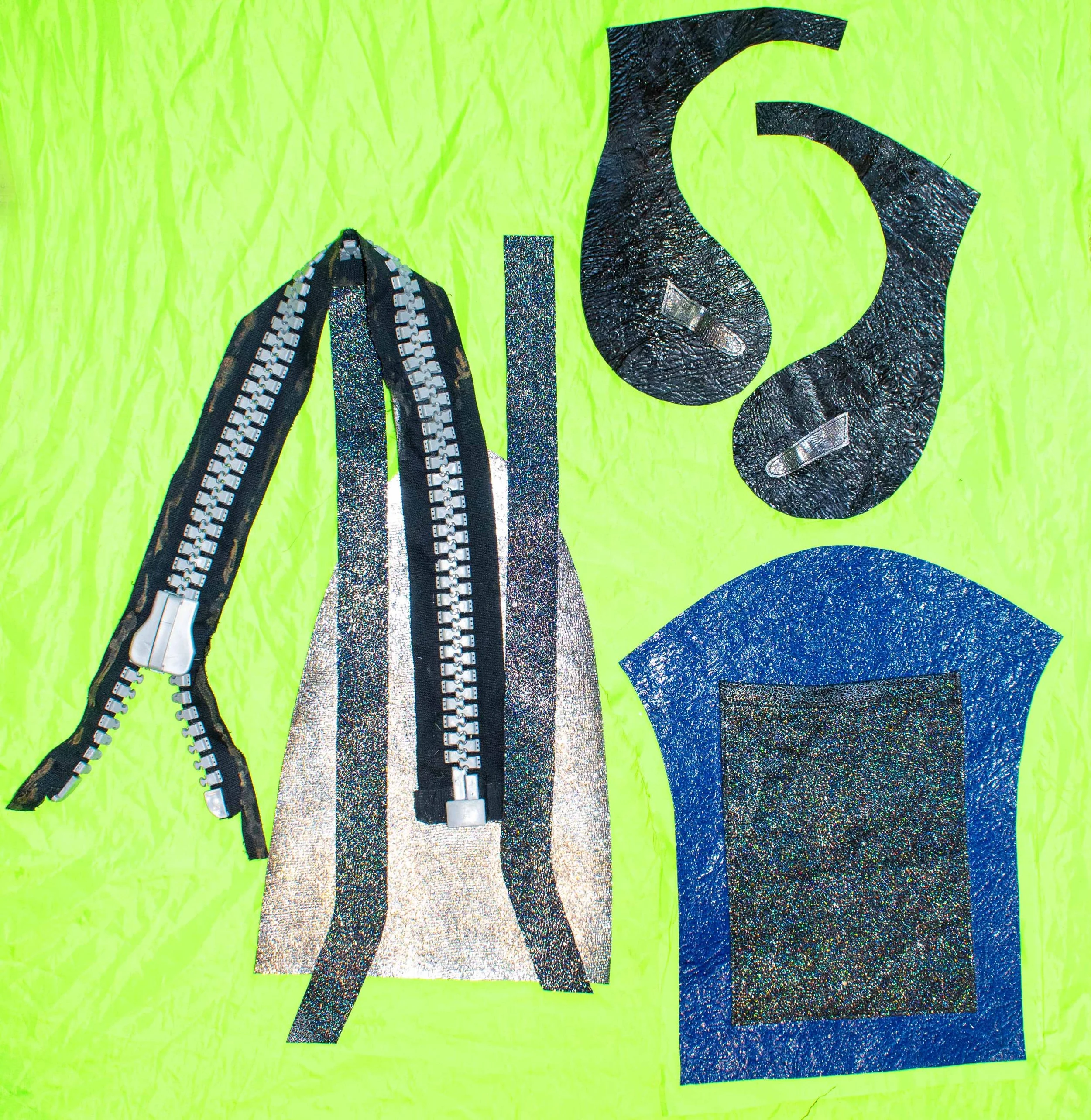 Colorful collage of fabric and zipper pieces arranged on a light green background.