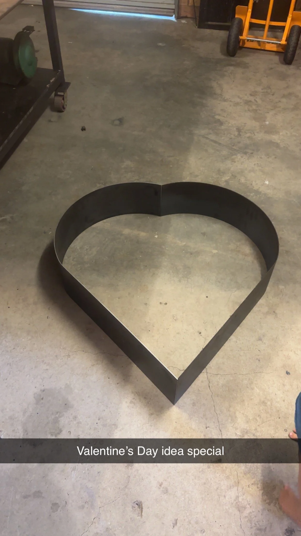 A metal heart-shaped on a concrete floor with a caption saying 'Valentine’s Day idea special'.