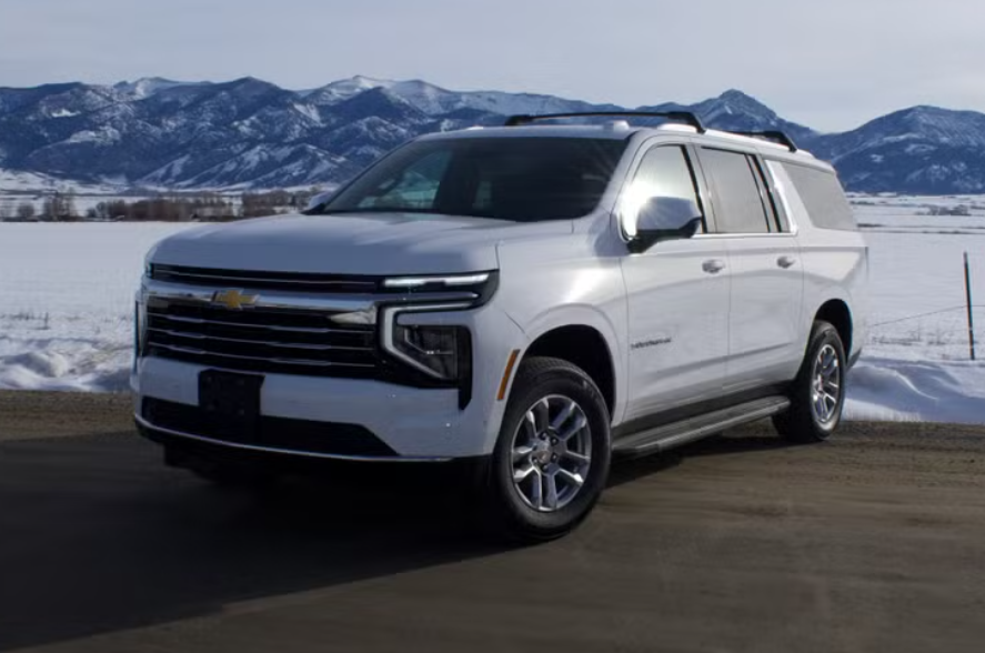 A silver Chevrolet SUV parked on a road with snow-covered mountains in the background.