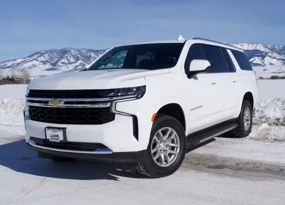 White Chevrolet SUV parked on snowy ground with mountains in the background.