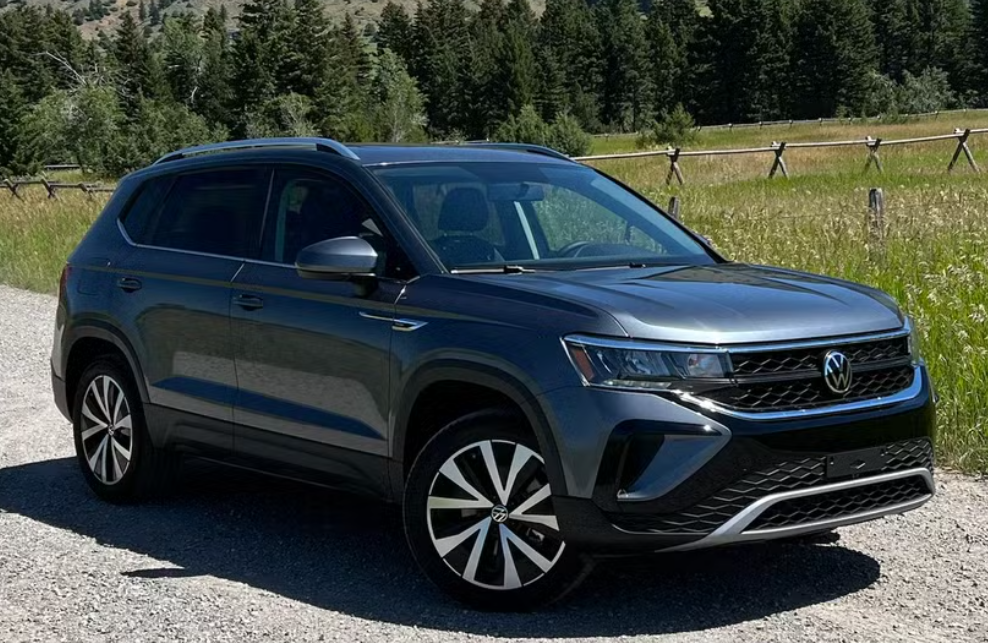 A black Volkswagen SUV parked on a gravel road in a rural area with grass and trees in the background.