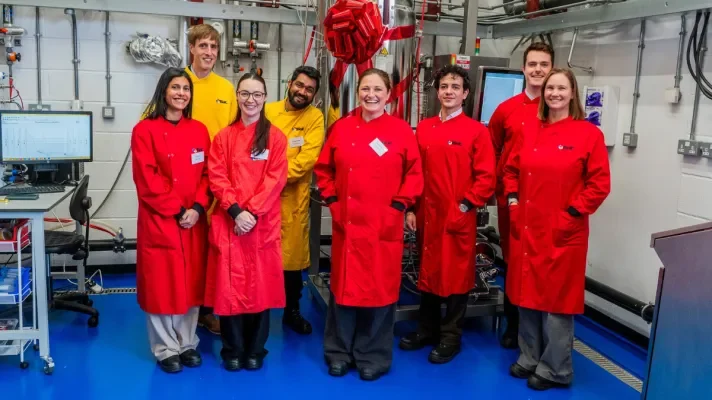 FlexBIO team in red lab coats standing in front of 300l fermenter at FlexBIO bioprocessing scale up facility in Edinburgh