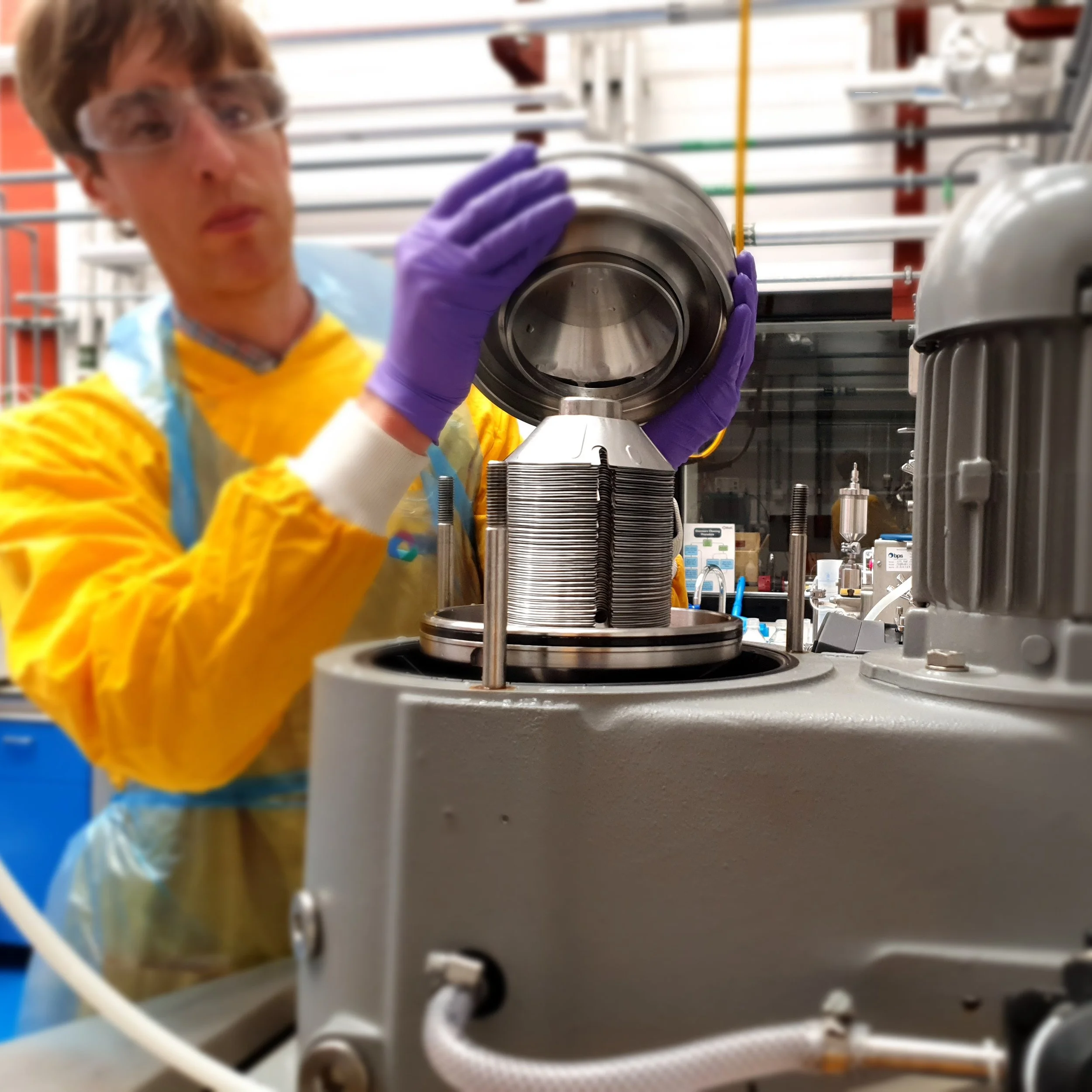 Scientist operating a disc stack centrifuge for cell separation and bioprocessing applications in a laboratory environment.