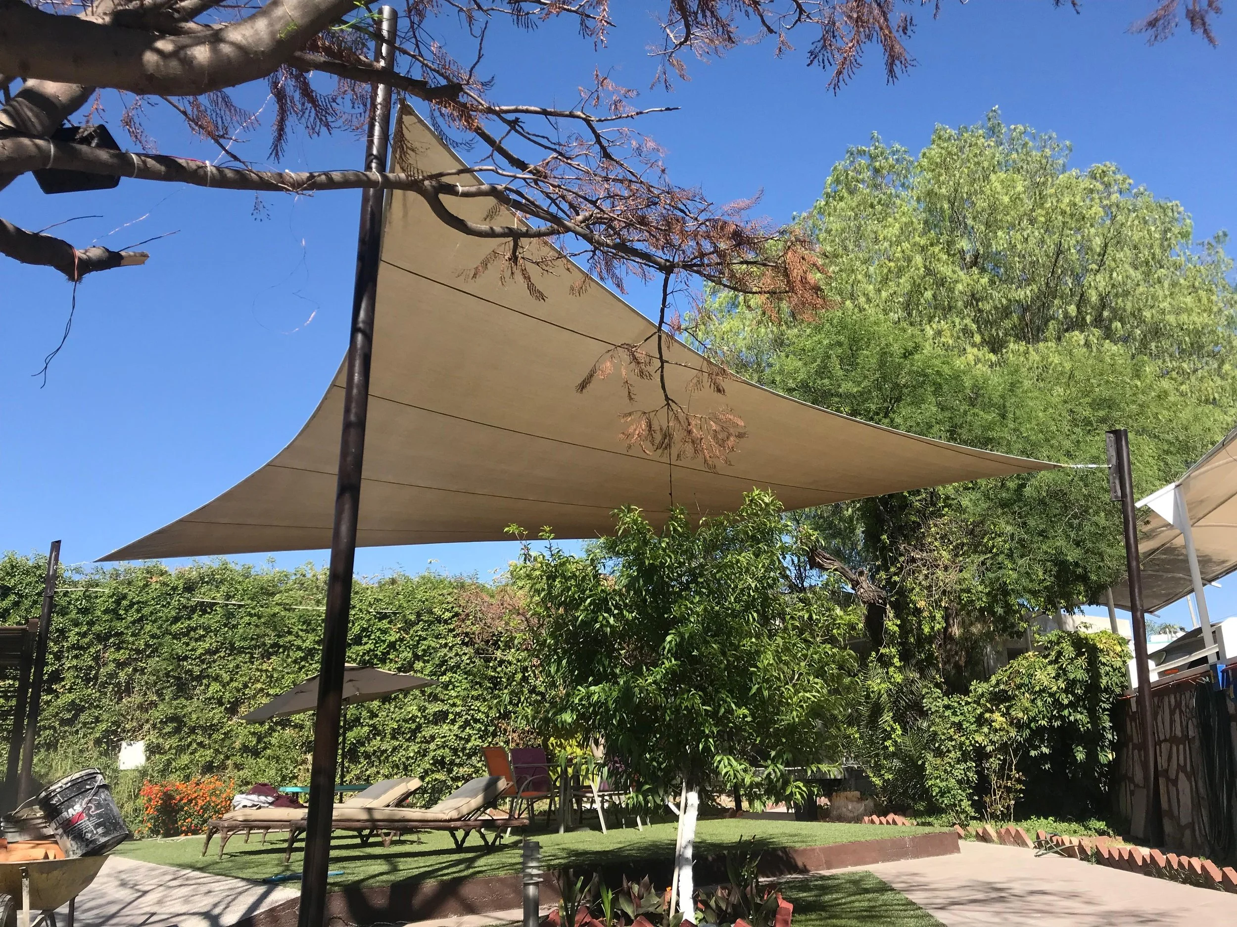 Sombrillas de tela en una terraza de jardín, rodeada de árboles y plantas.