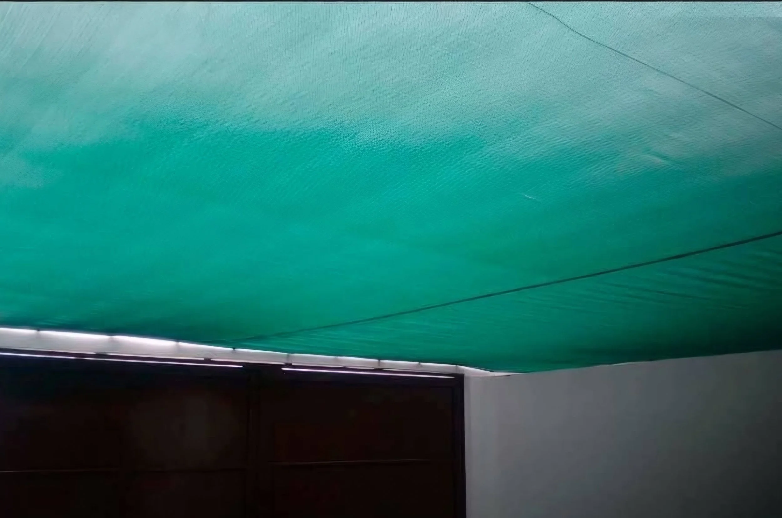 Techo cubierto con una lona verde parece un toldo o sombrilla en una casa.