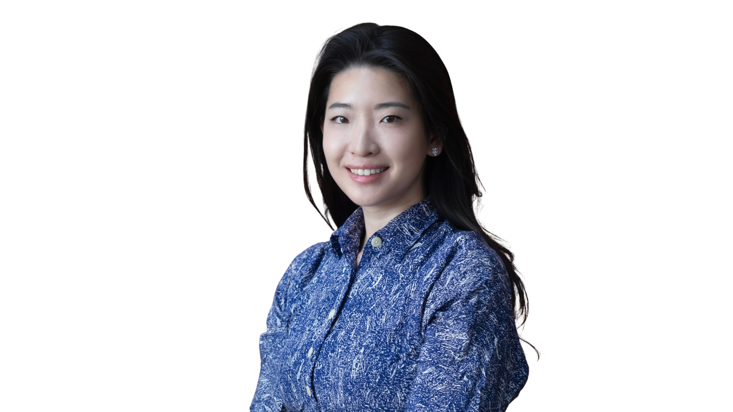 Black and white photo of a woman with long dark hair, smiling, wearing a patterned button-up shirt, against a black background.