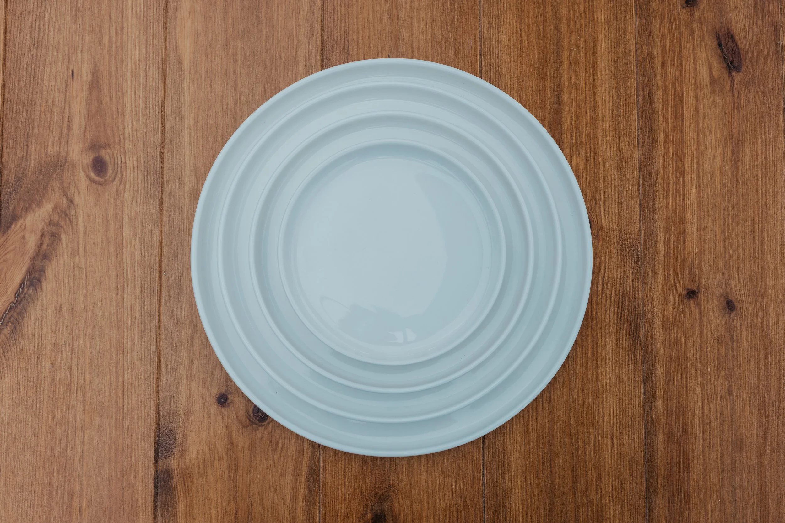 White ceramic plate with ridged concentric circles on a wooden table