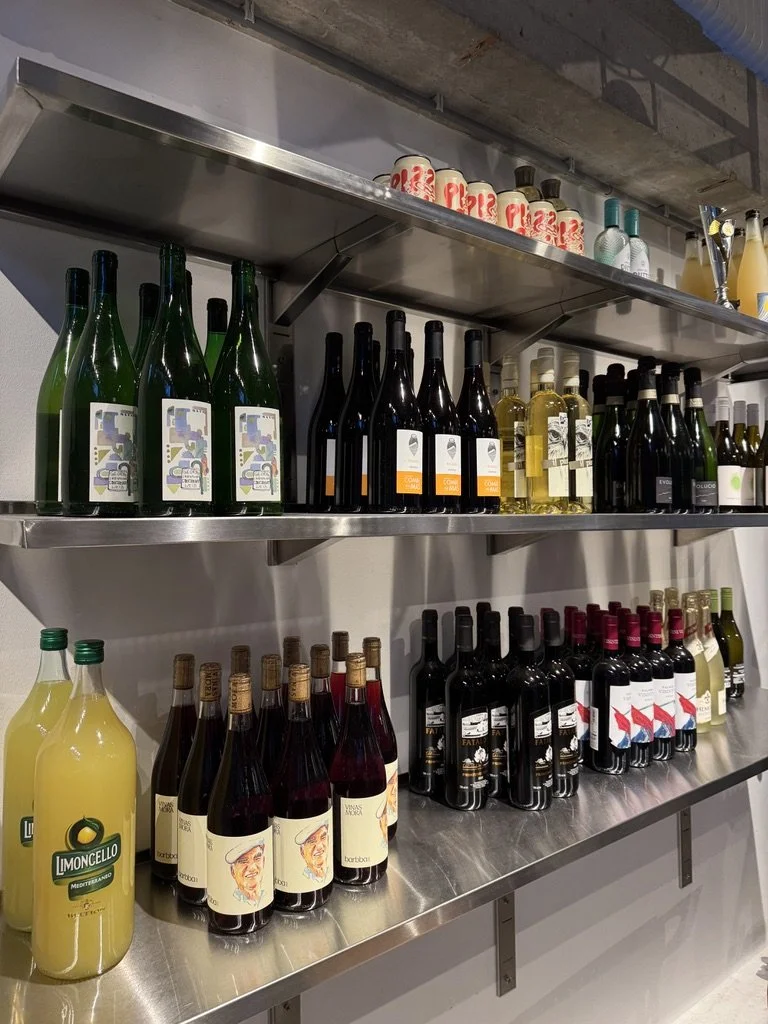 Display of various bottles of wine and beverages on metal shelves at a store.