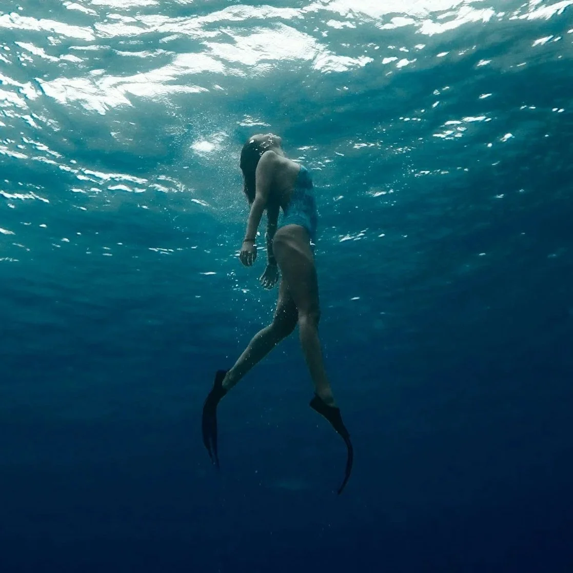 Underwater shot of a woman with a mermaid tail swimming in the ocean.
