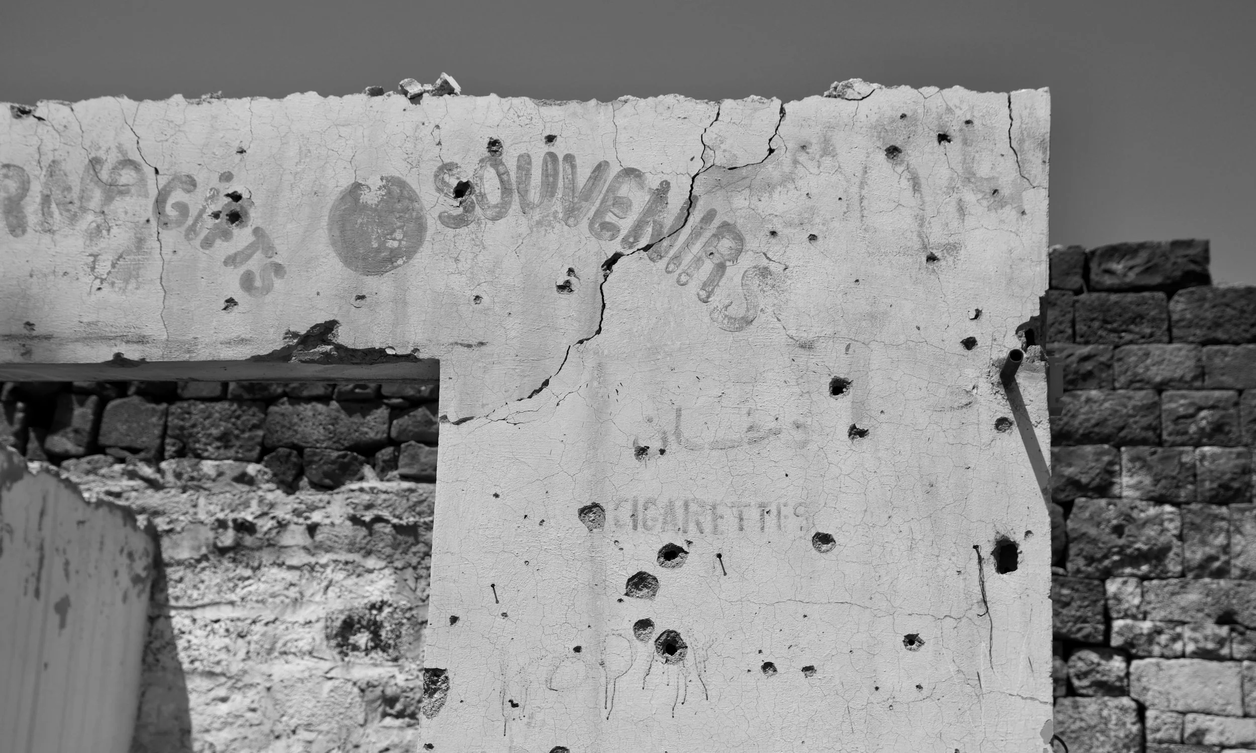 Mur d'un ancien magasin de souvenirs, criblé de traces de balles. Datant de la guerre de Syrie. Photo en noir et blanc