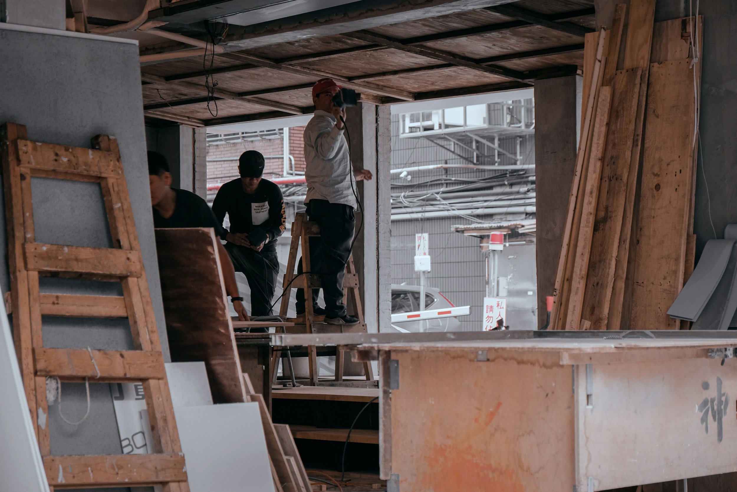 Construction workers inside a building under renovation, with wooden planks and construction materials around.