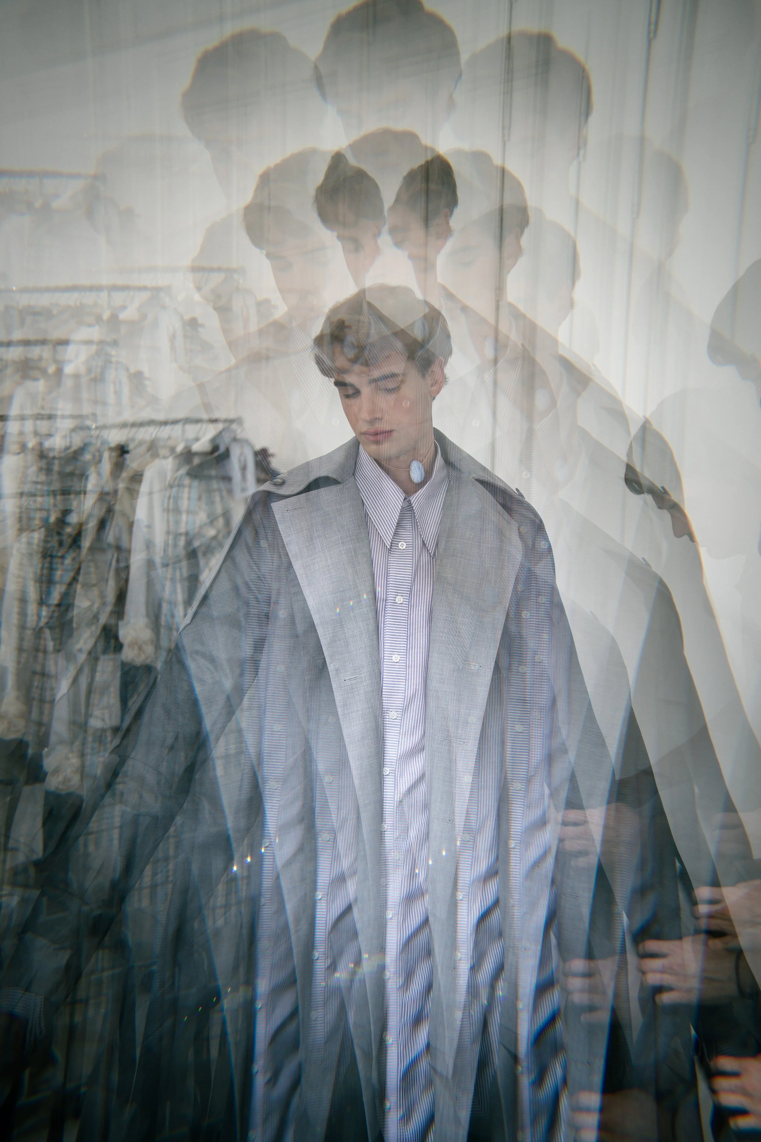 A person looking down inside a clothing store, with multiple overlapping images creating a layered, ghost-like effect.
