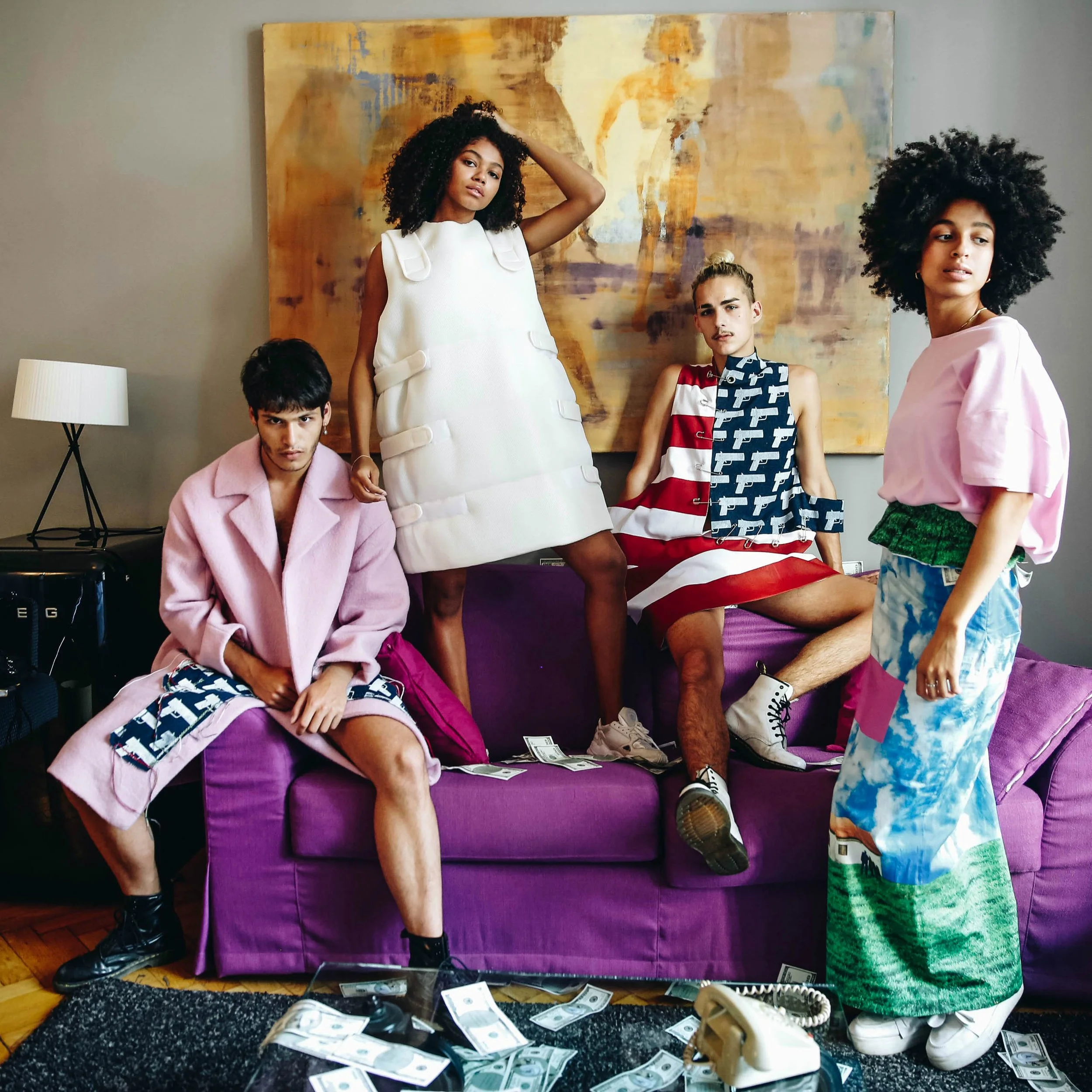 Five young people with diverse styles posing in a living room with a purple couch, abstract art, and scattered money on the floor.