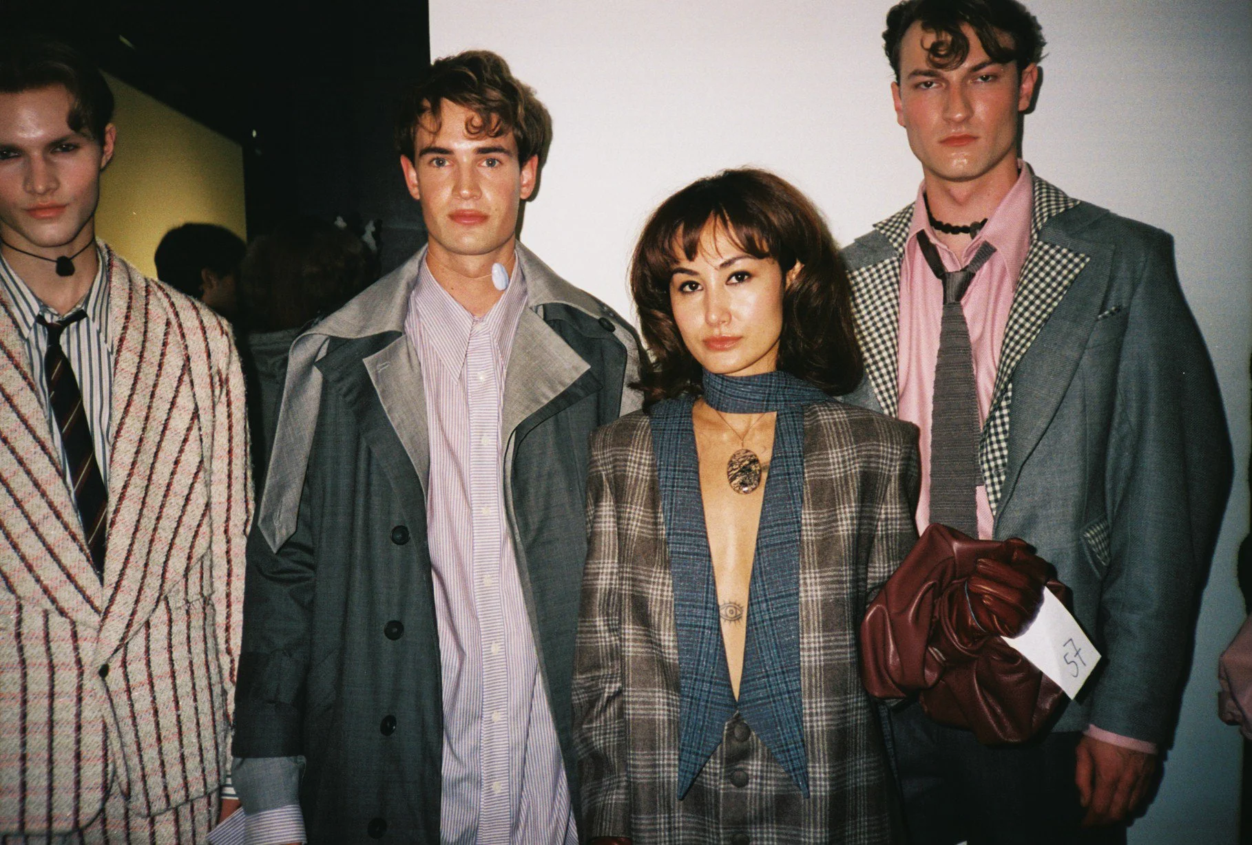 Group of young adults at a fashion event, dressed in eclectic, vintage-inspired clothing, standing against a plain background.