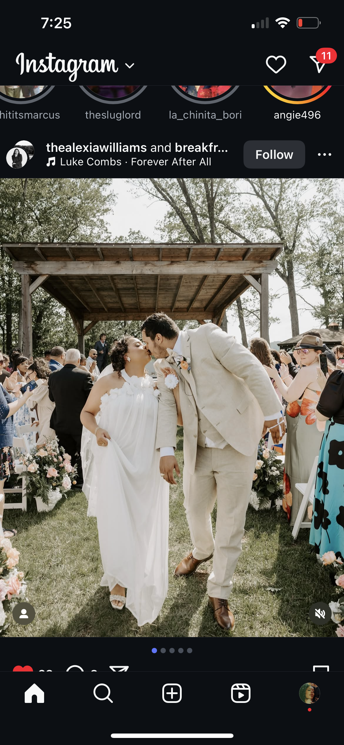 A couple shares a kiss at their outdoor wedding ceremony, surrounded by friends and family, with floral arrangements and a wooden canopy.