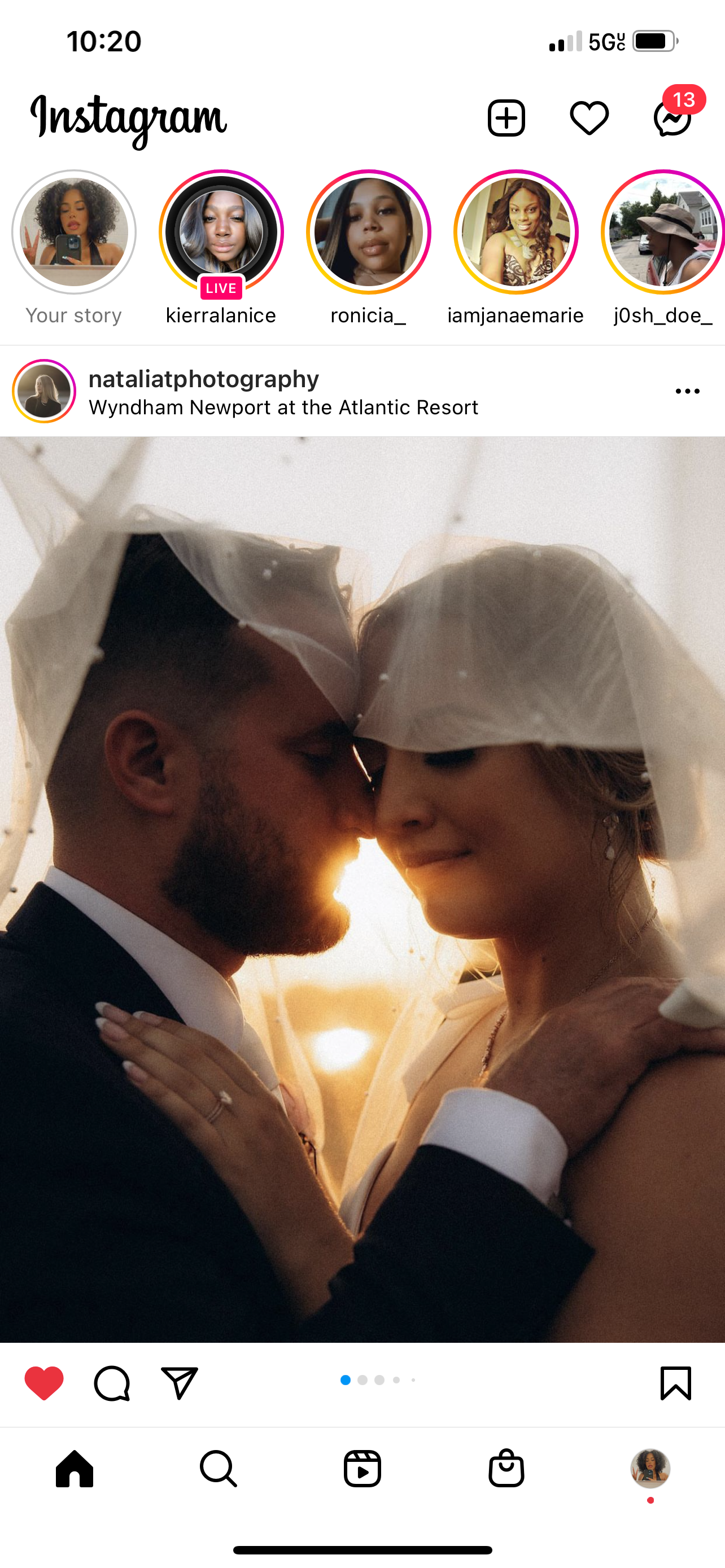 A romantic wedding photo of a bride and groom with their foreheads touching, partially covered by a wedding veil, at sunset.