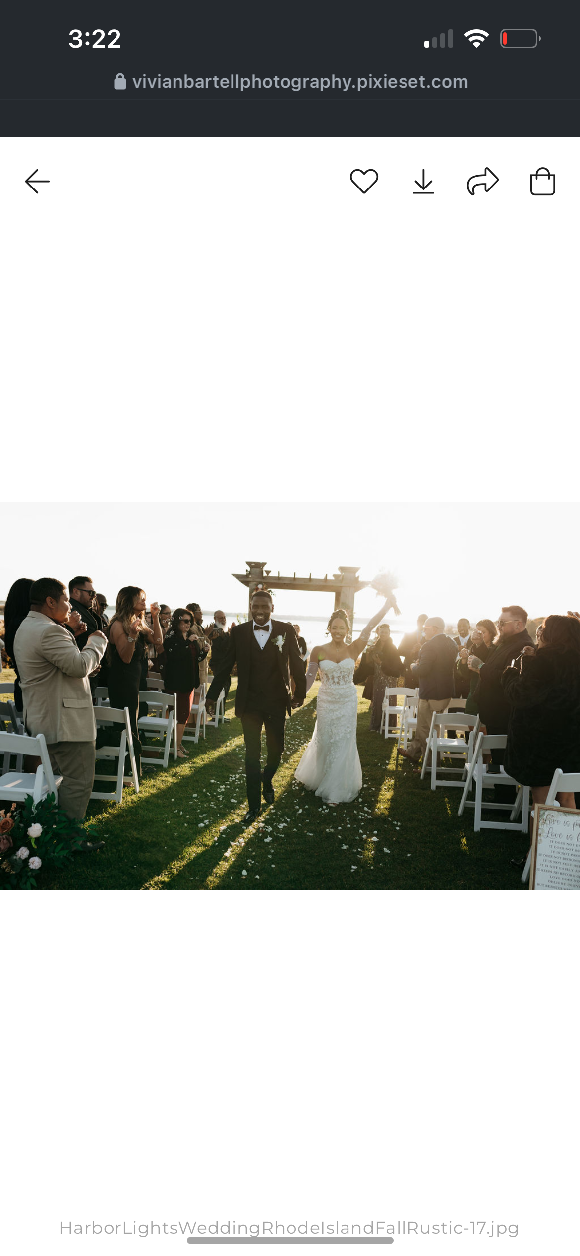 Newly married couple walking down the aisle at their outdoor wedding as guests celebrate and take photos.