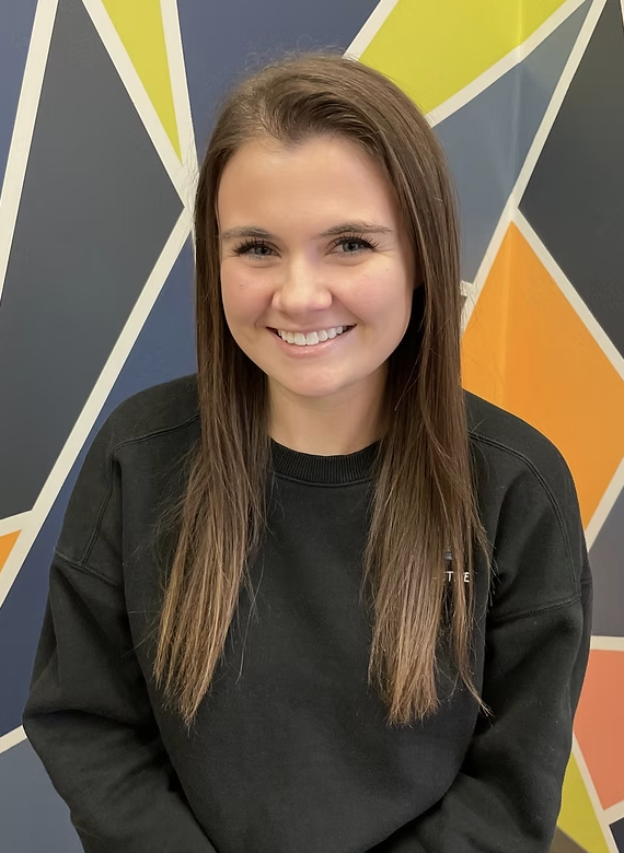 Blue icon of a smiling person wearing a helmet or protective headgear, set against a dark background.