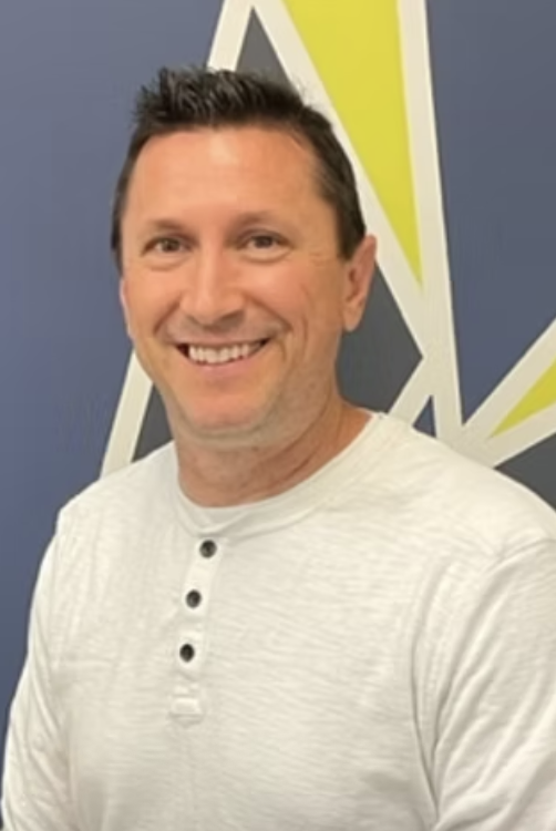 Blue icon of a smiling person wearing a helmet or protective headgear, set against a dark background.