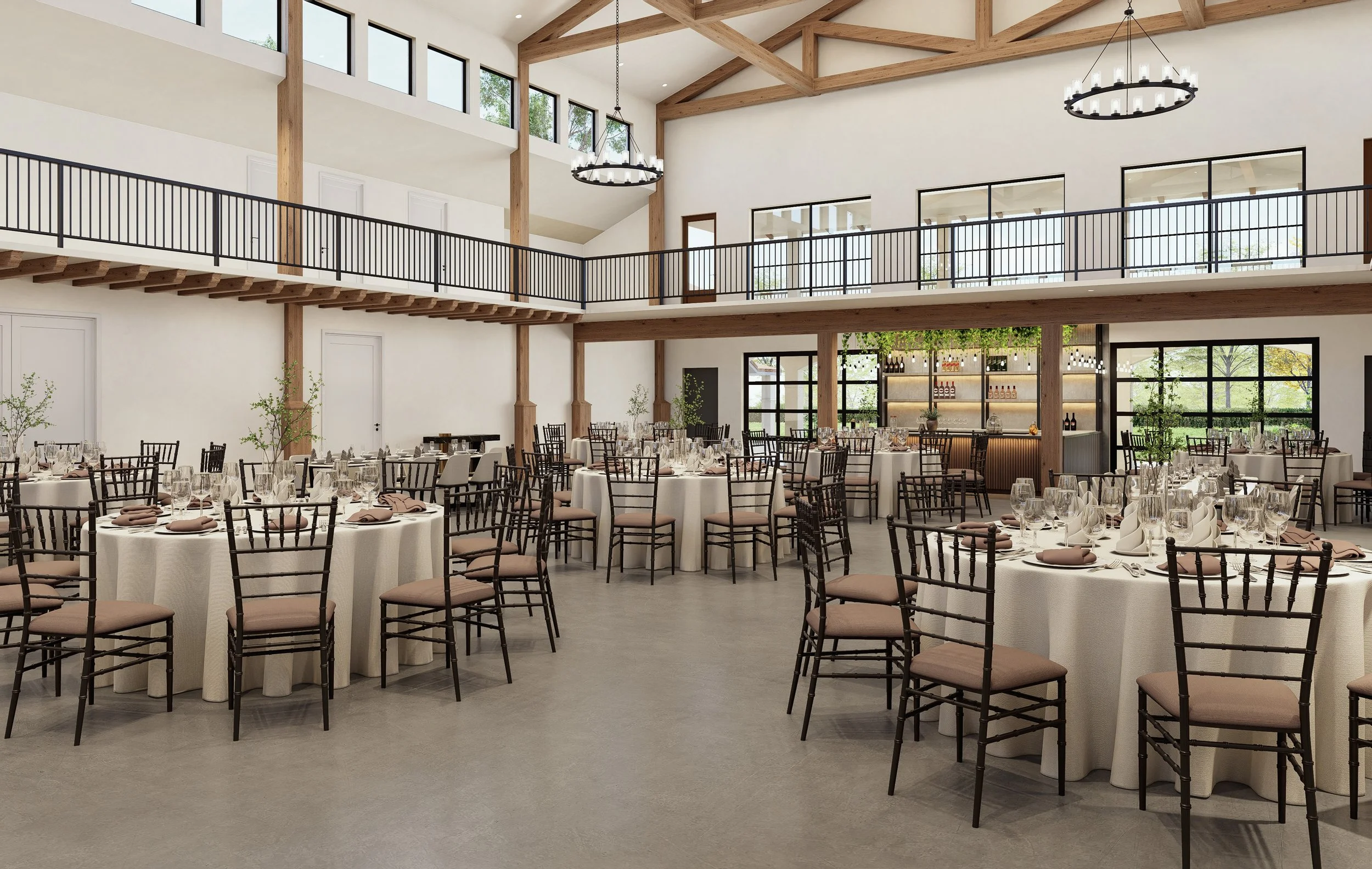 Elegant event space with round tables covered in white tablecloths, set for a formal dinner, surrounded by brown chairs with cushioned seats. The room has high ceilings with wooden beams, large windows, and modern chandeliers. There is a bar area at the back with shelves filled with bottles and glasses, and some greenery accents.