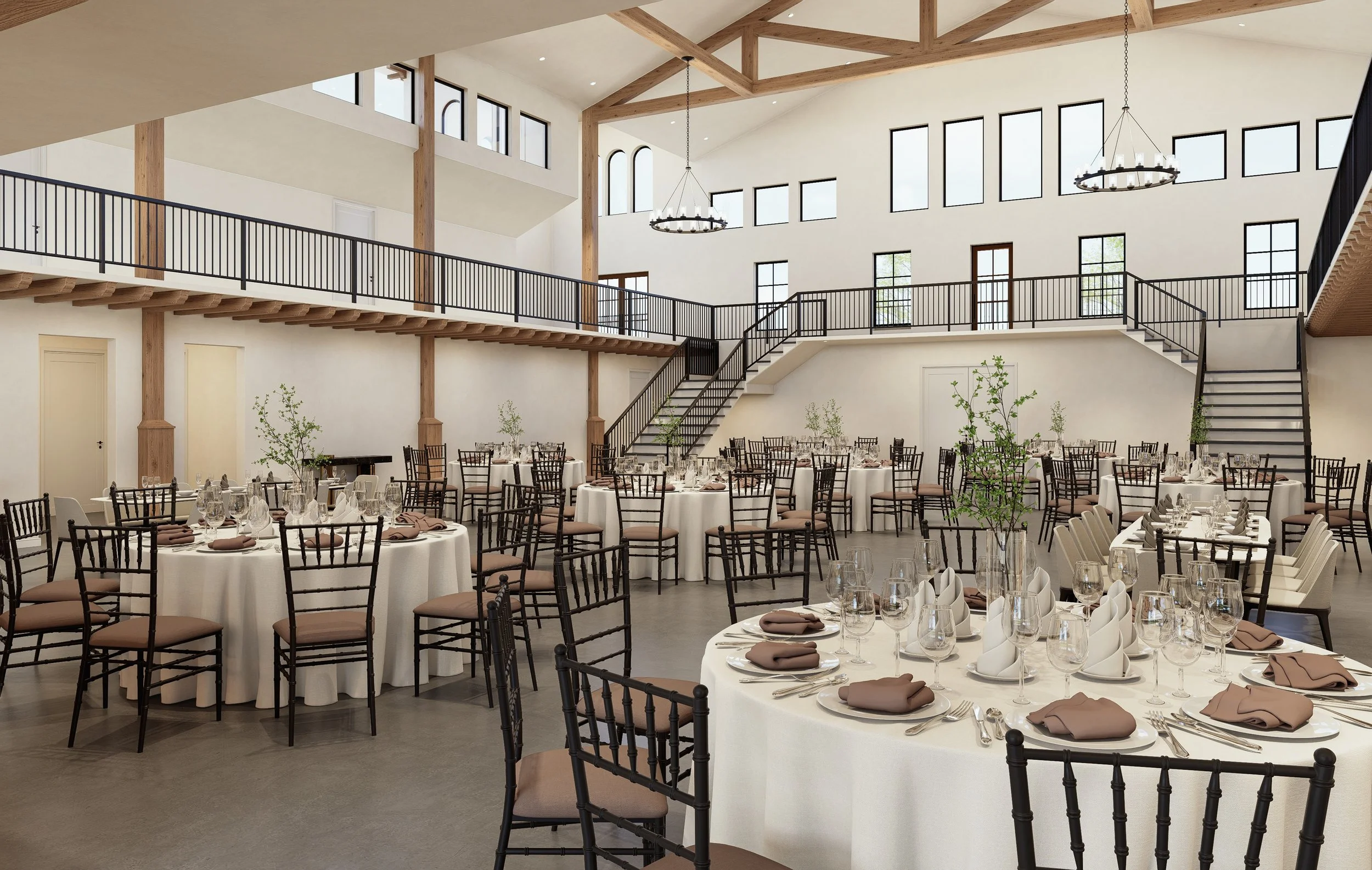 Elegant banquet hall with round tables draped in white tablecloths, set with glassware, plates, and napkins, surrounded by black chairs with beige cushions, featuring an upstairs balcony, wooden beams, large windows, and chandelier lighting.