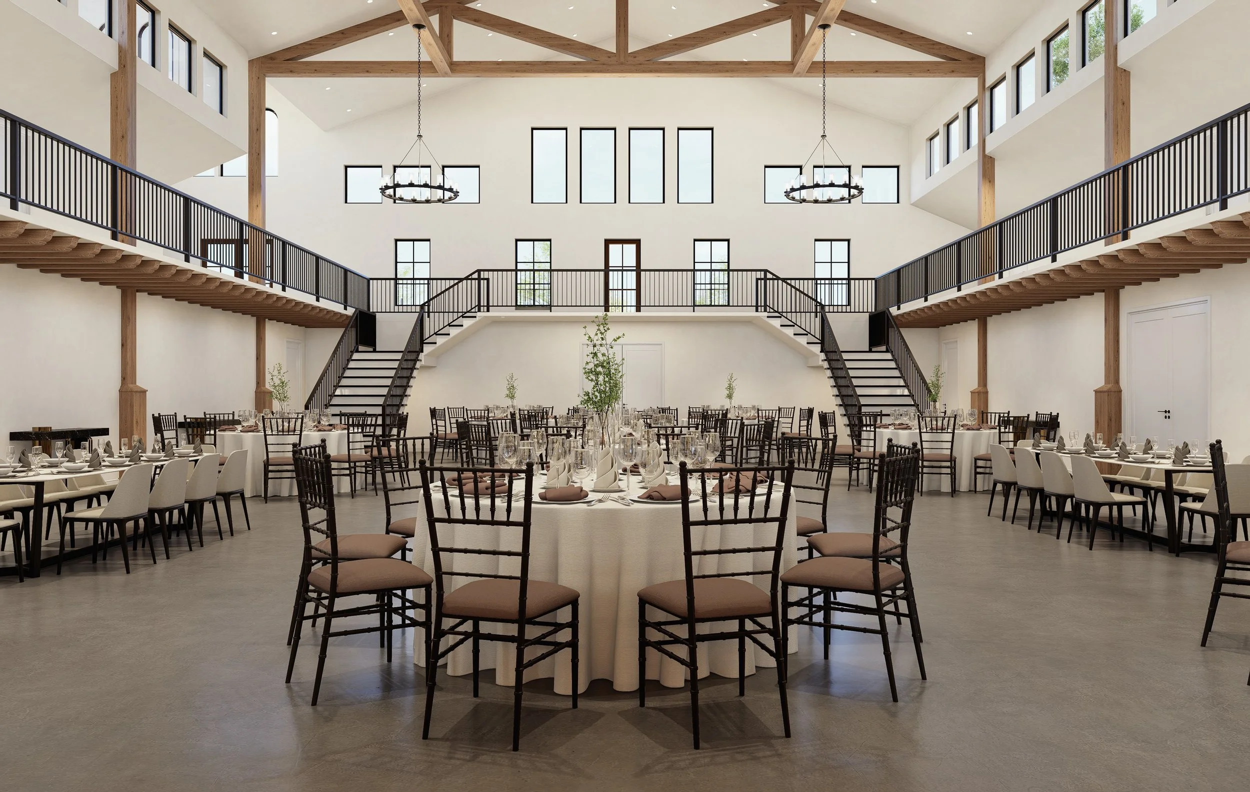 Elegant banquet hall with round and rectangular tables set with napkins, glassware, and centerpieces, featuring a high ceiling with wooden beams, large windows, and a balcony with staircases on either side.