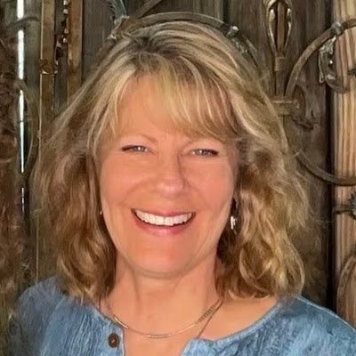 Patty is a white woman, wearing a blue shirt, smiling & looking at the camera