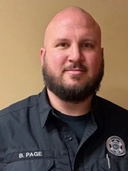 Ben is a white man, in a policeman's uniform looking at the camera