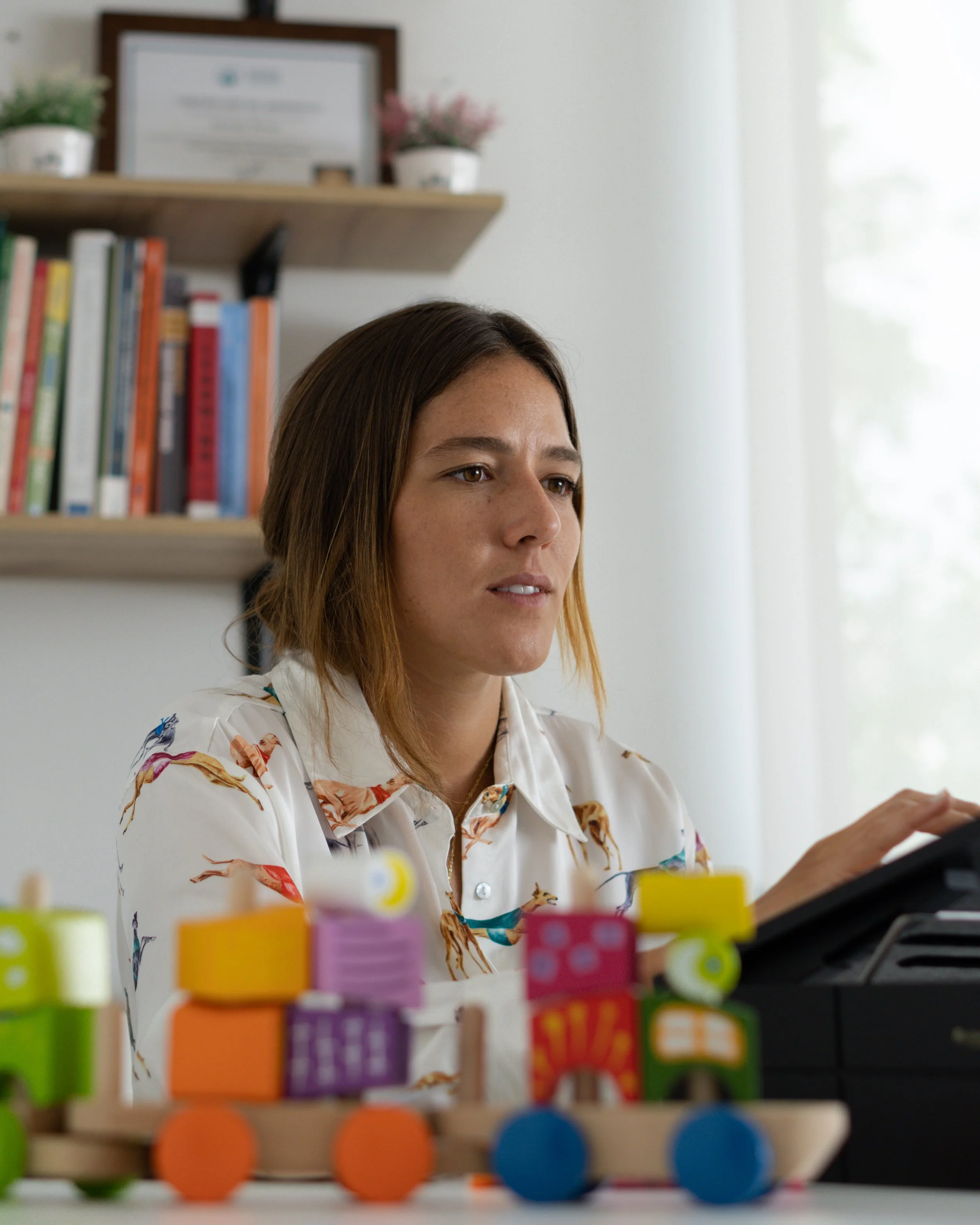 Mujer trabajando en una oficina con juguetes de madera en primer plano.