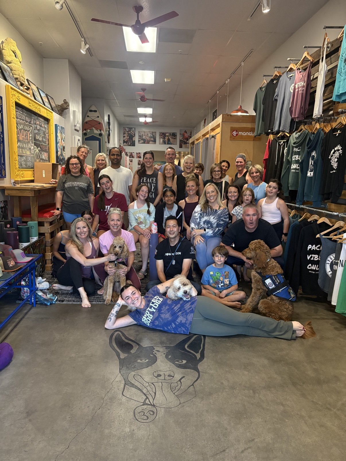 The Yoga + Pups group photo in the Spotted Dog Yoga & SUP lobby with the Paw Platoon therapy dogs