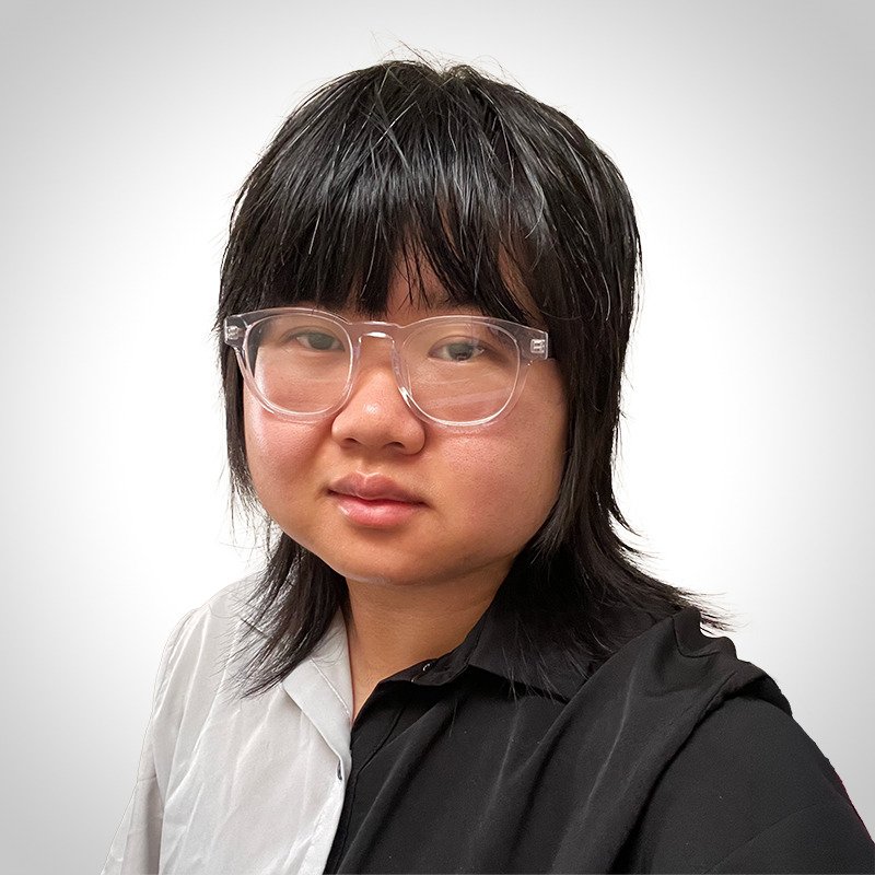 A young man with medium-length black hair, wearing clear glasses, one half white and the other half black shirt, against a plain white background.