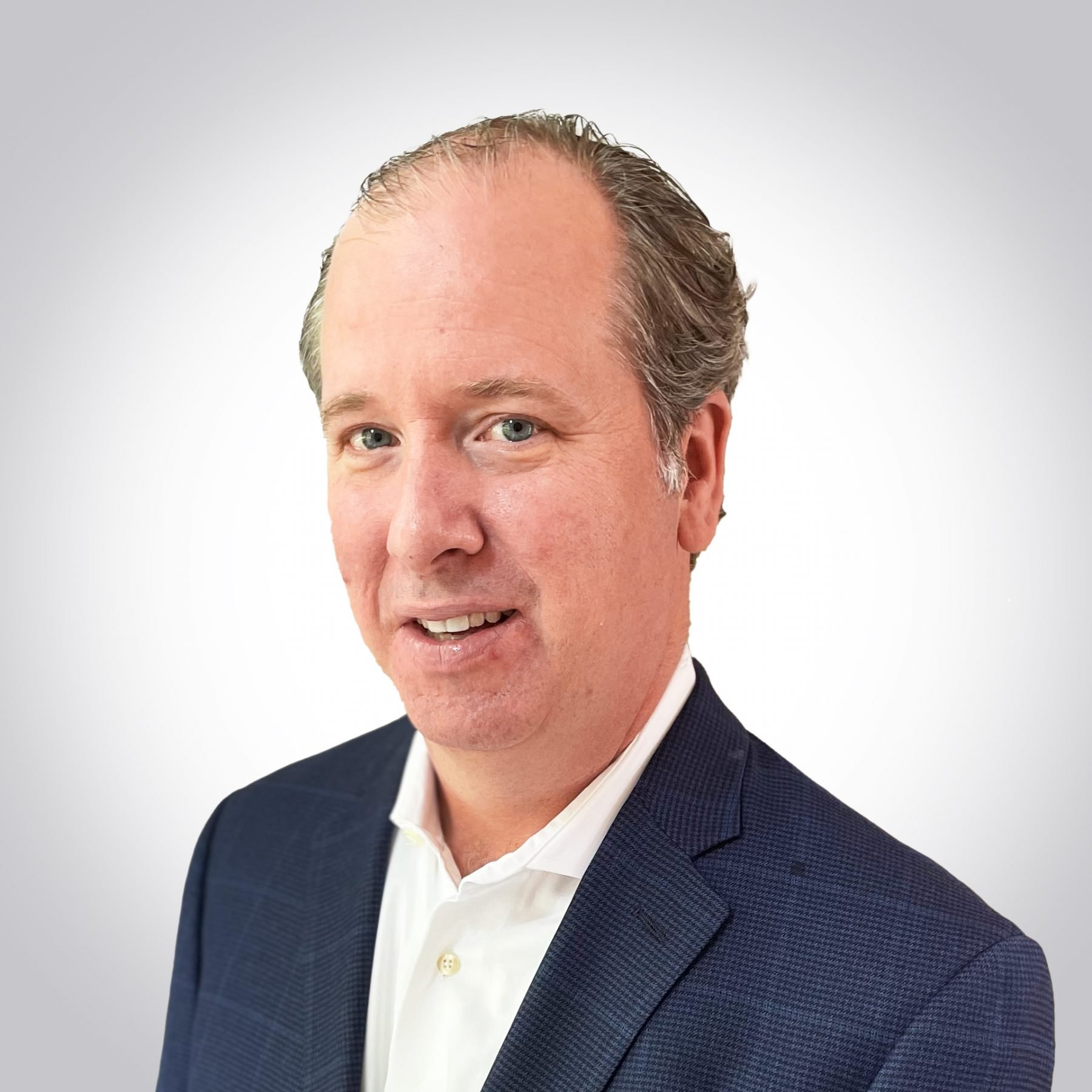 A man wearing a dark suit jacket and white shirt poses against a white background.