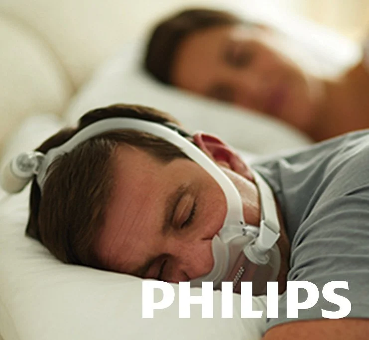 Two men sleeping on beds, one with a sleep apnea mask, branded Philips.