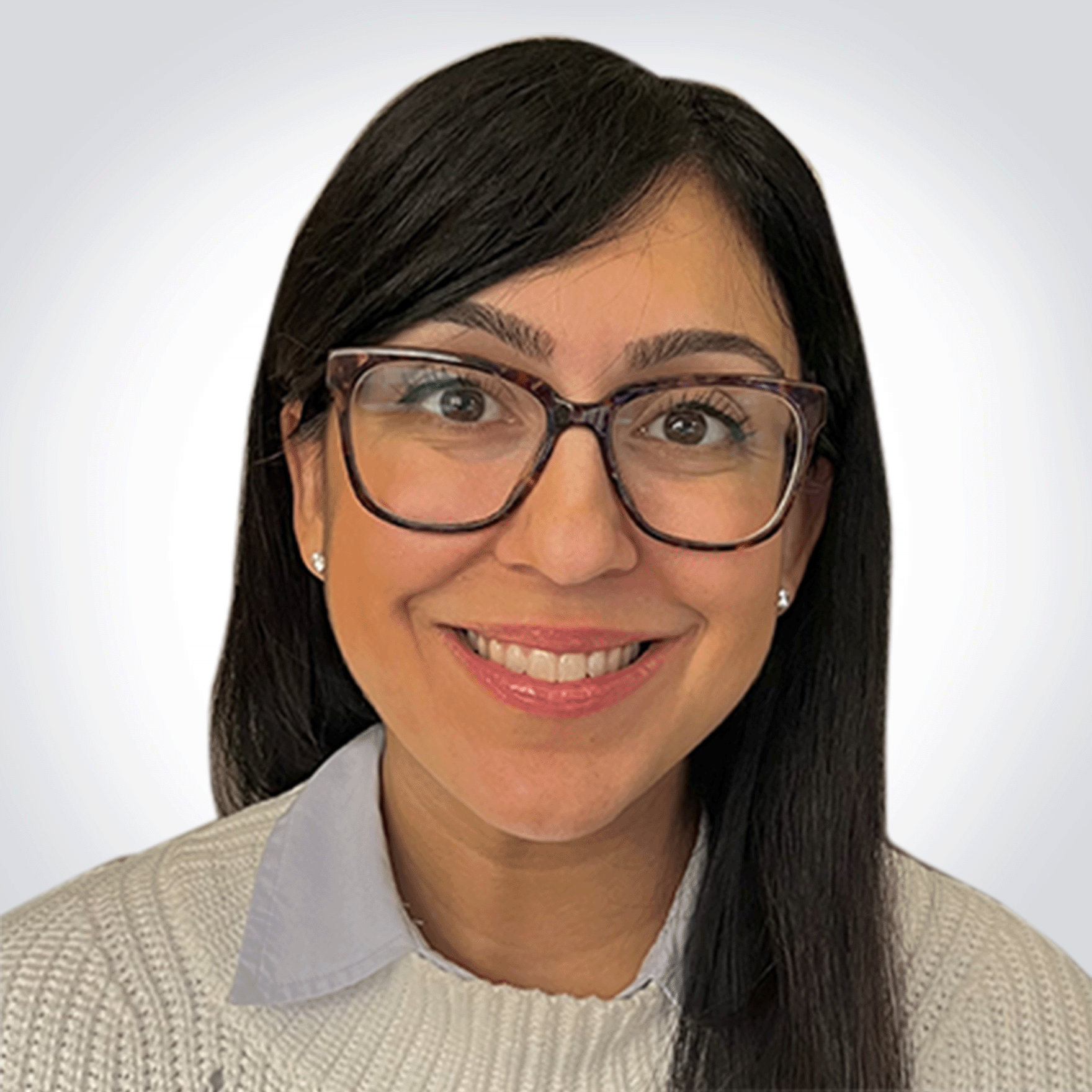 A woman with straight, dark hair, wearing glasses with a tortoiseshell pattern, smiling, dressed in a white sweater and collared shirt, against a plain white background.