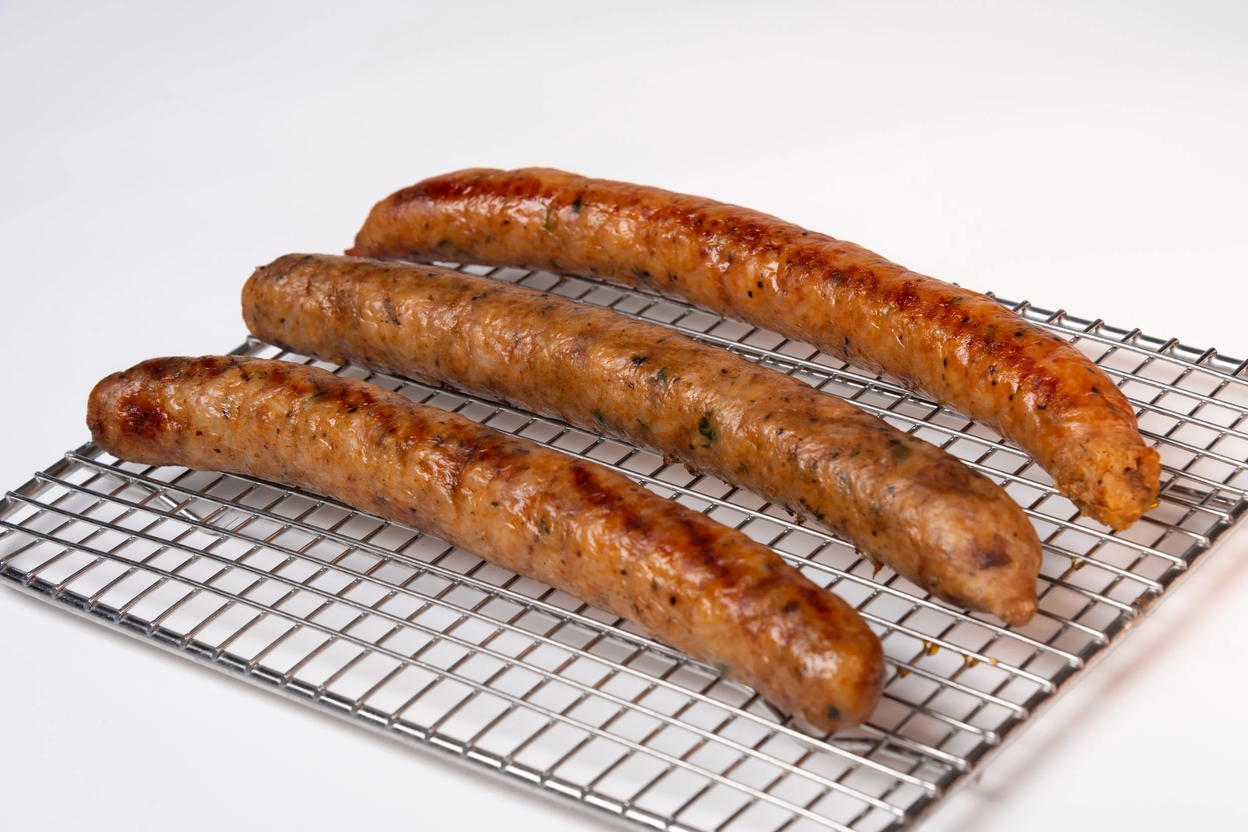 Three cooked boudin on a metal cooling rack.
